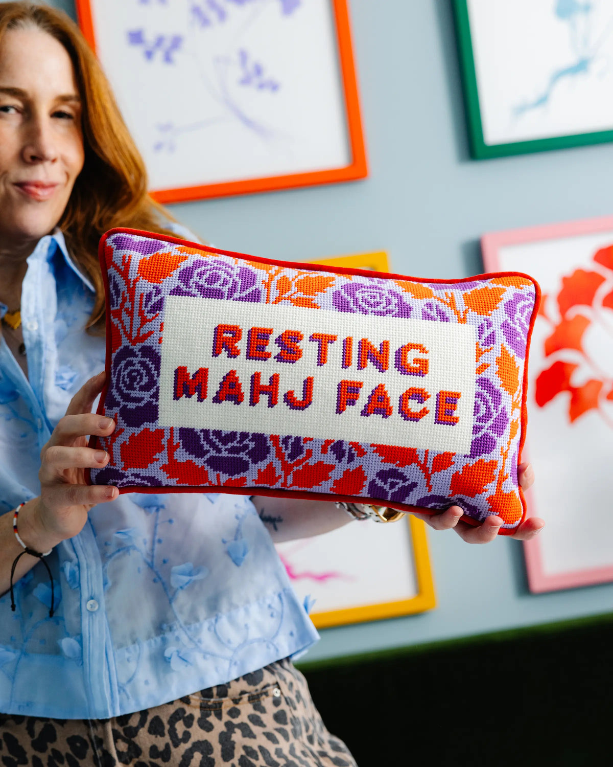 Needlepoint decorative pillow with 'RESTING MAHJ FACE' on purple patterned fabric, red trim