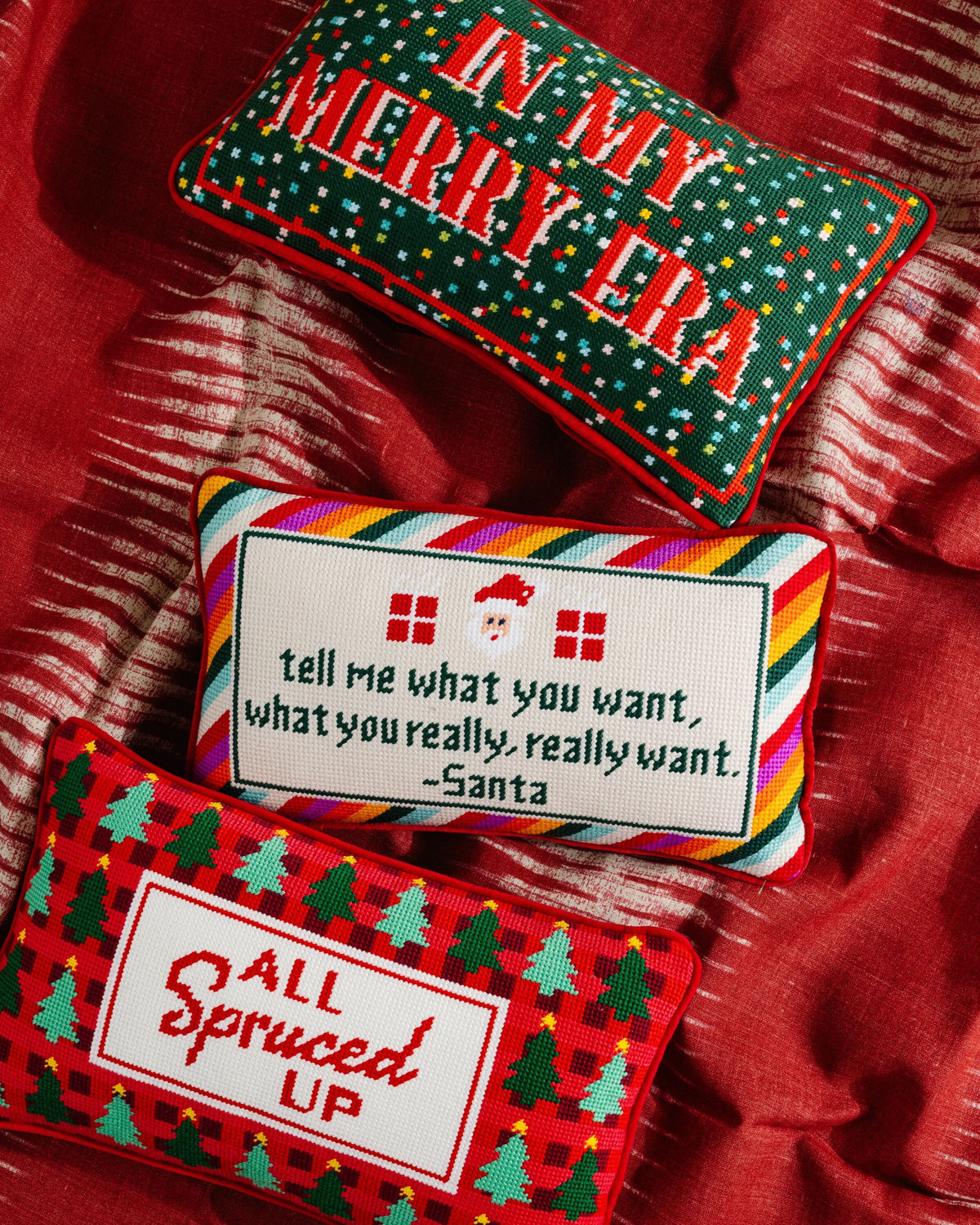 Red needlepoint pillow with green border and Merry Era stitched lettering