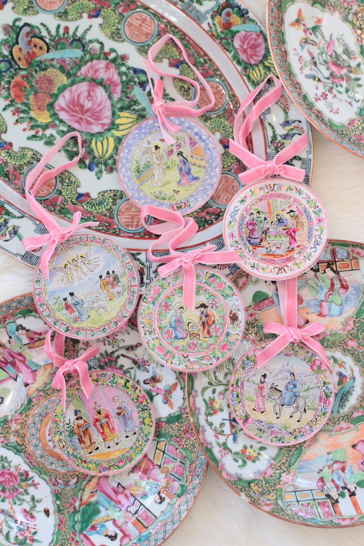 Magi ornament among assorted round illustrated ornaments with pink ribbons