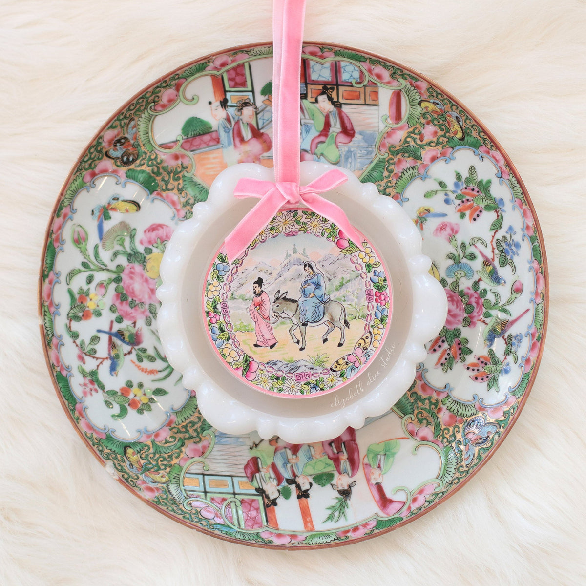 Acrylic ornament with pink velvet bow and floral frame around the Bethlehem journey scene