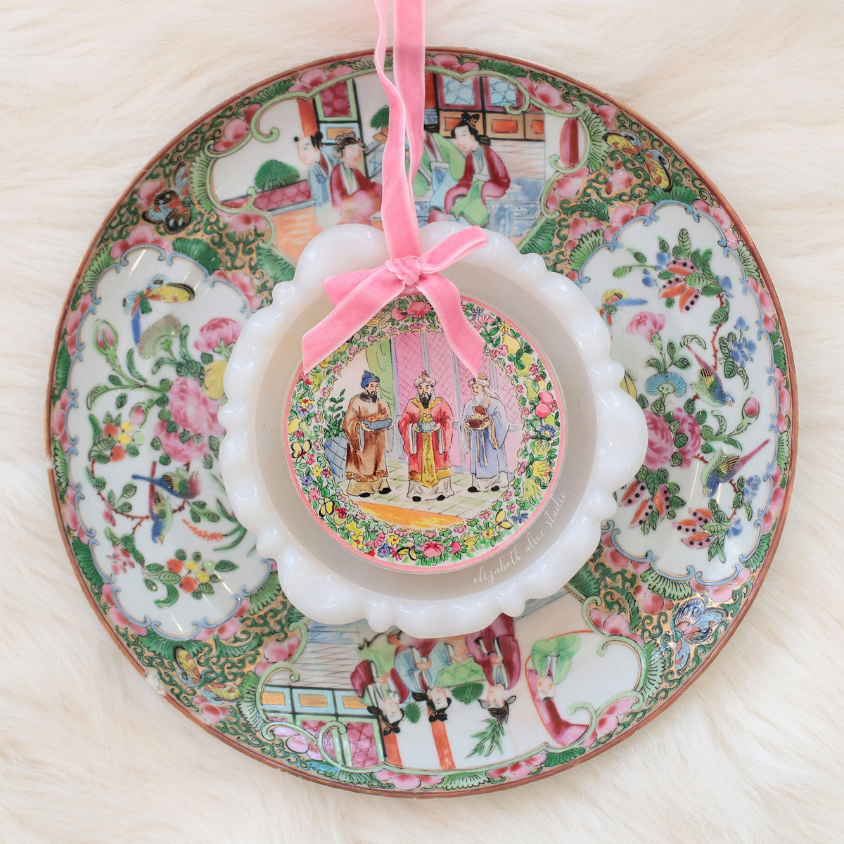 Magi ornament with pink bow, displayed over a decorative plate
