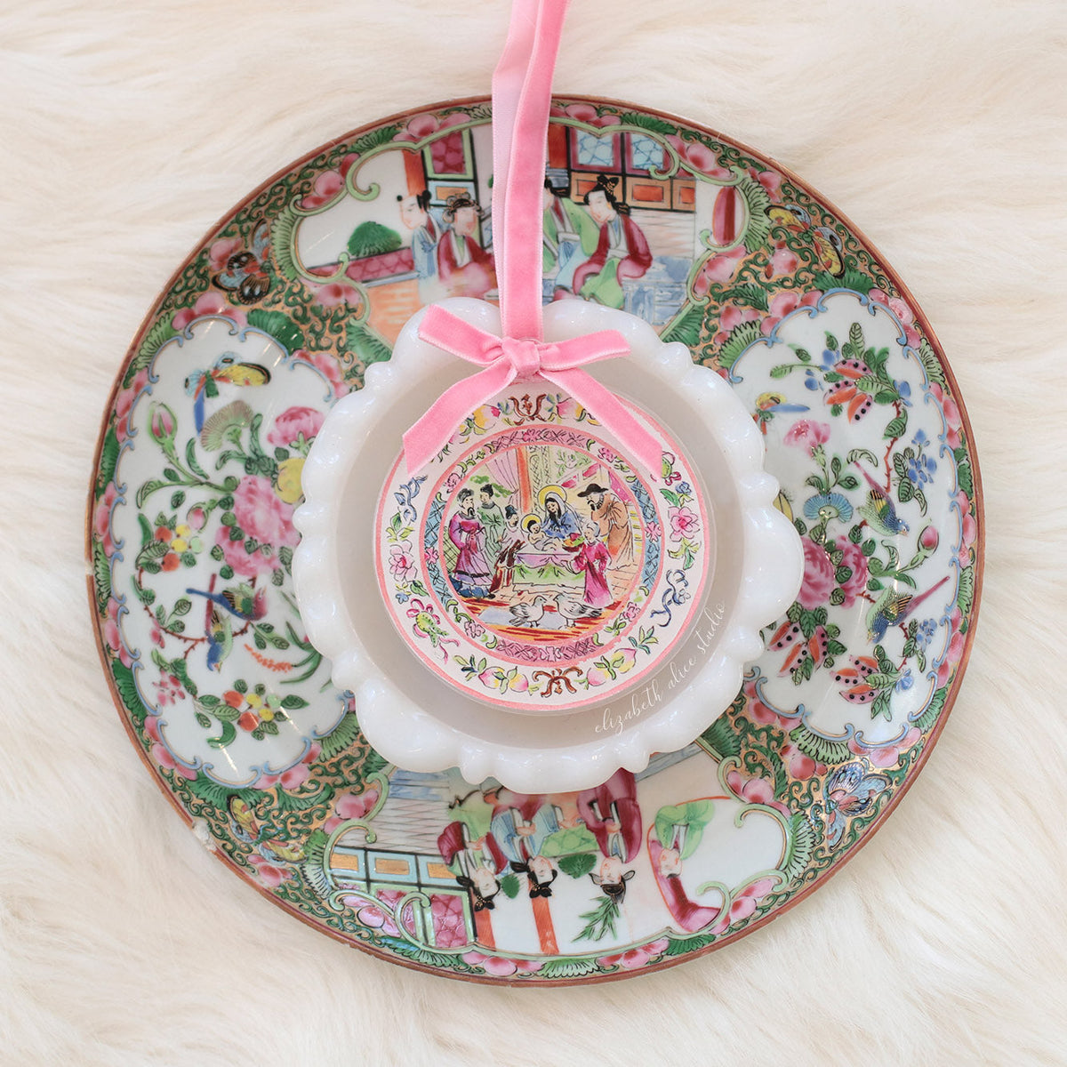 Round temple scene ornament with pink bow displayed over a decorative plate