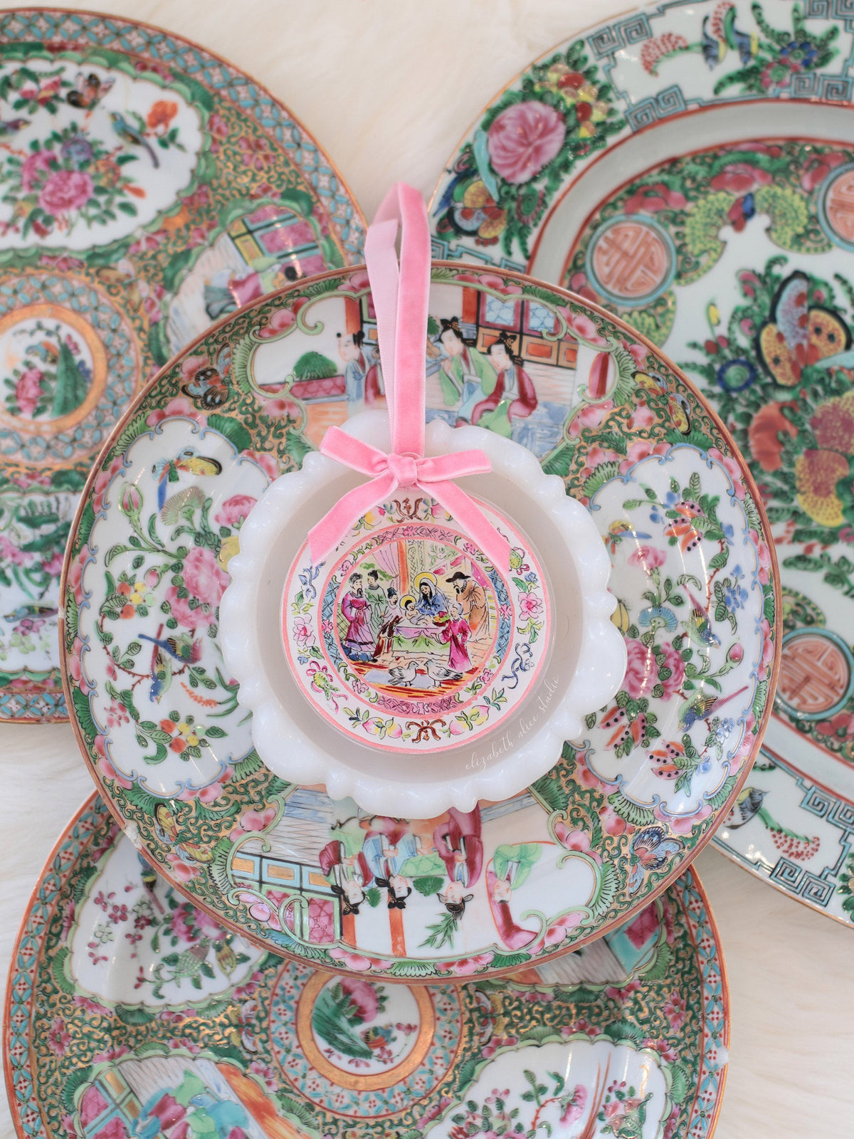 Small round temple scene ornament with pink bow, displayed against decorative plates