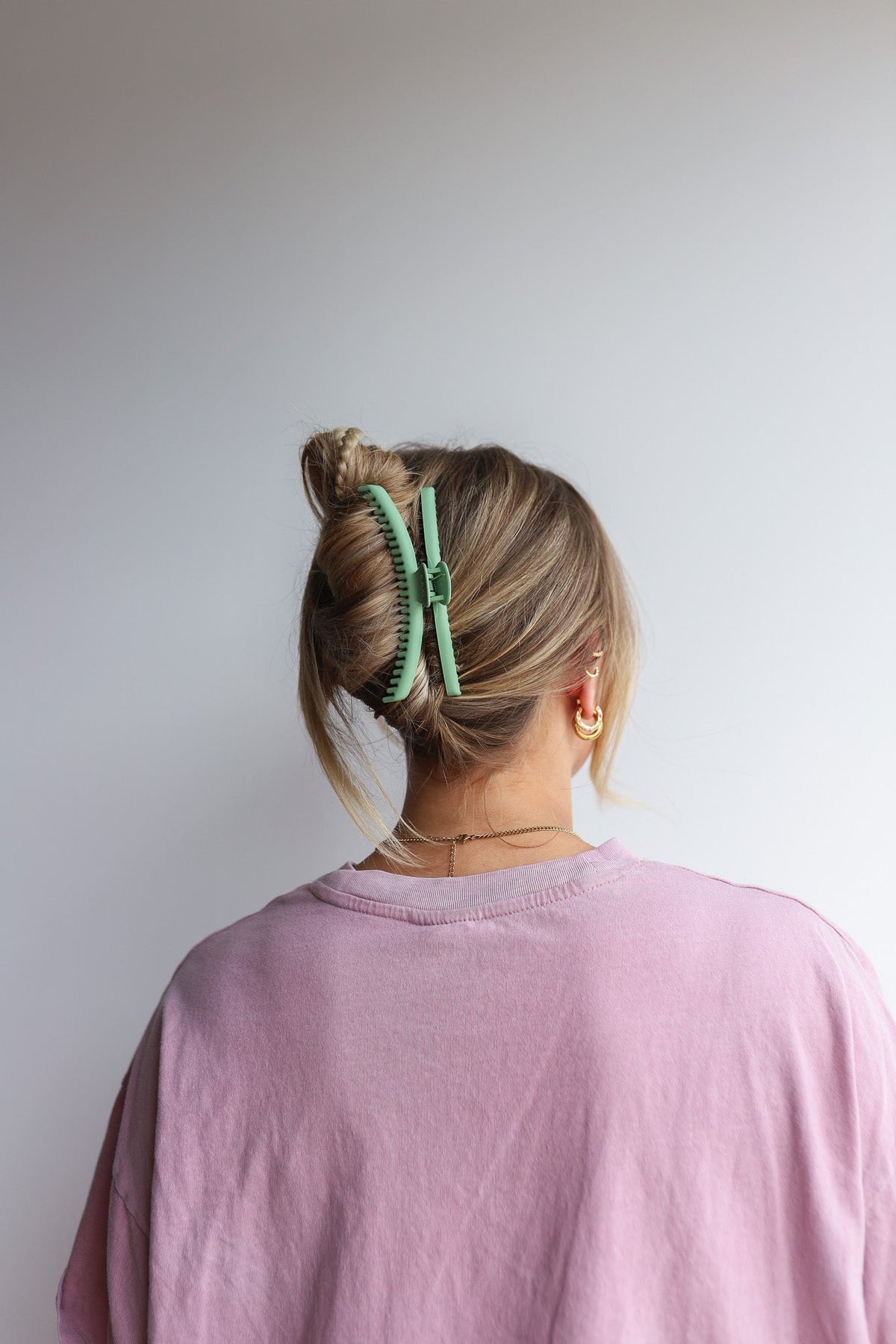 Green hair claw clip secured on a low bun, back view