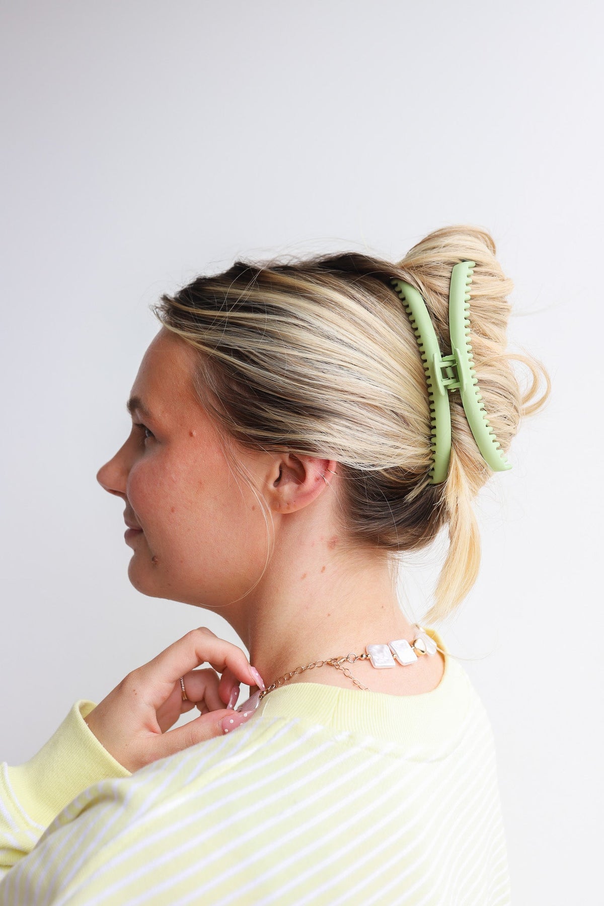 Mint green hair claw clip on blonde ponytail, front side view