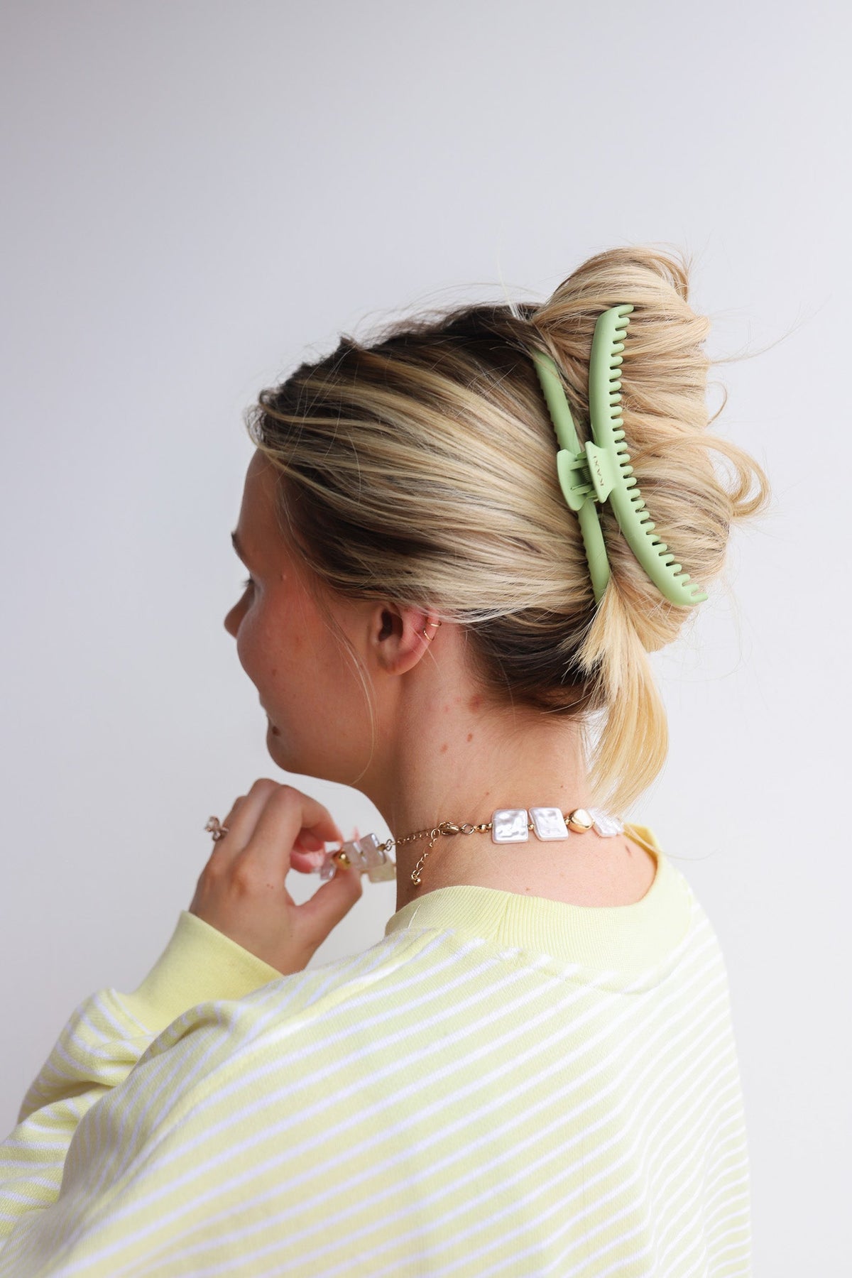 Mint green hair claw clip holding blonde hair in a bun