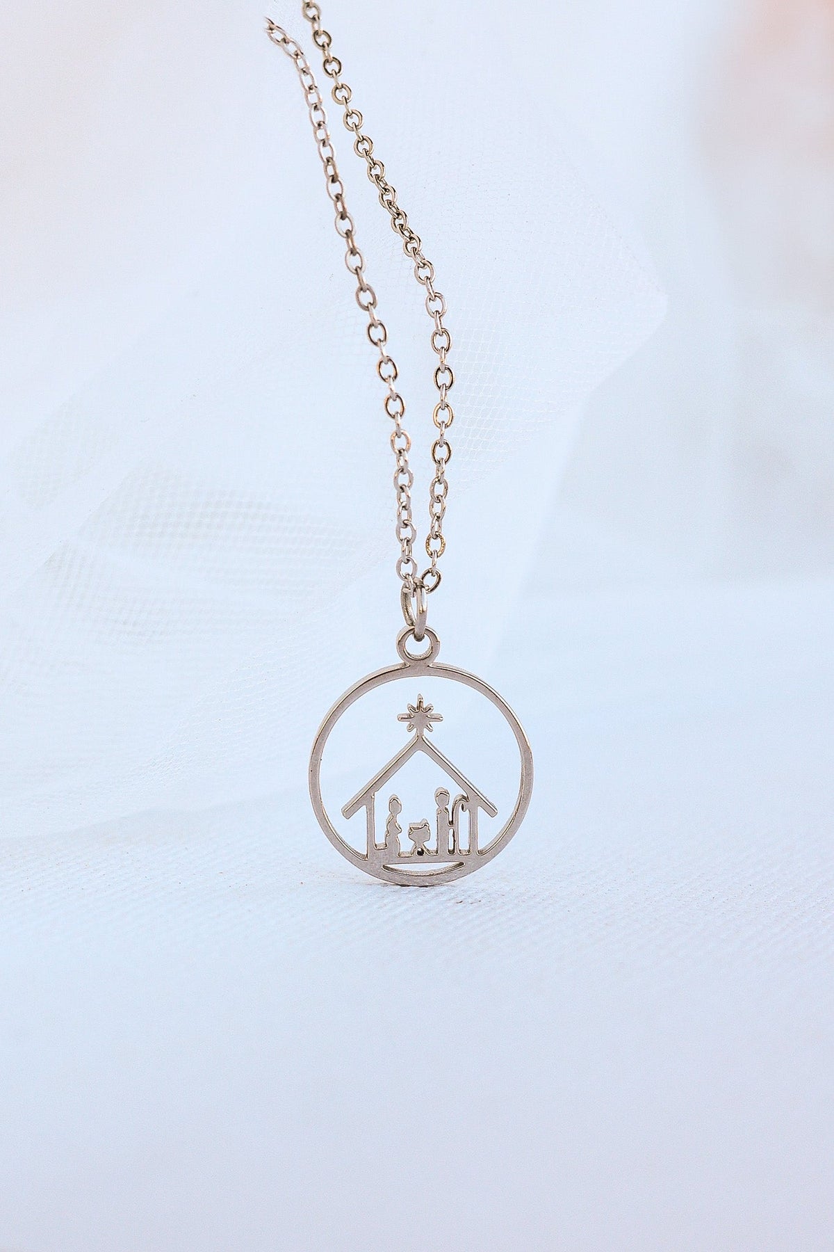 Gold-tone chain necklace with a circular Nativity scene pendant.