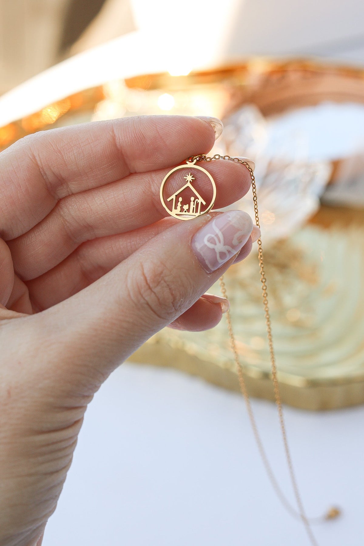 Gold Nativity necklace pendant held close to show its design