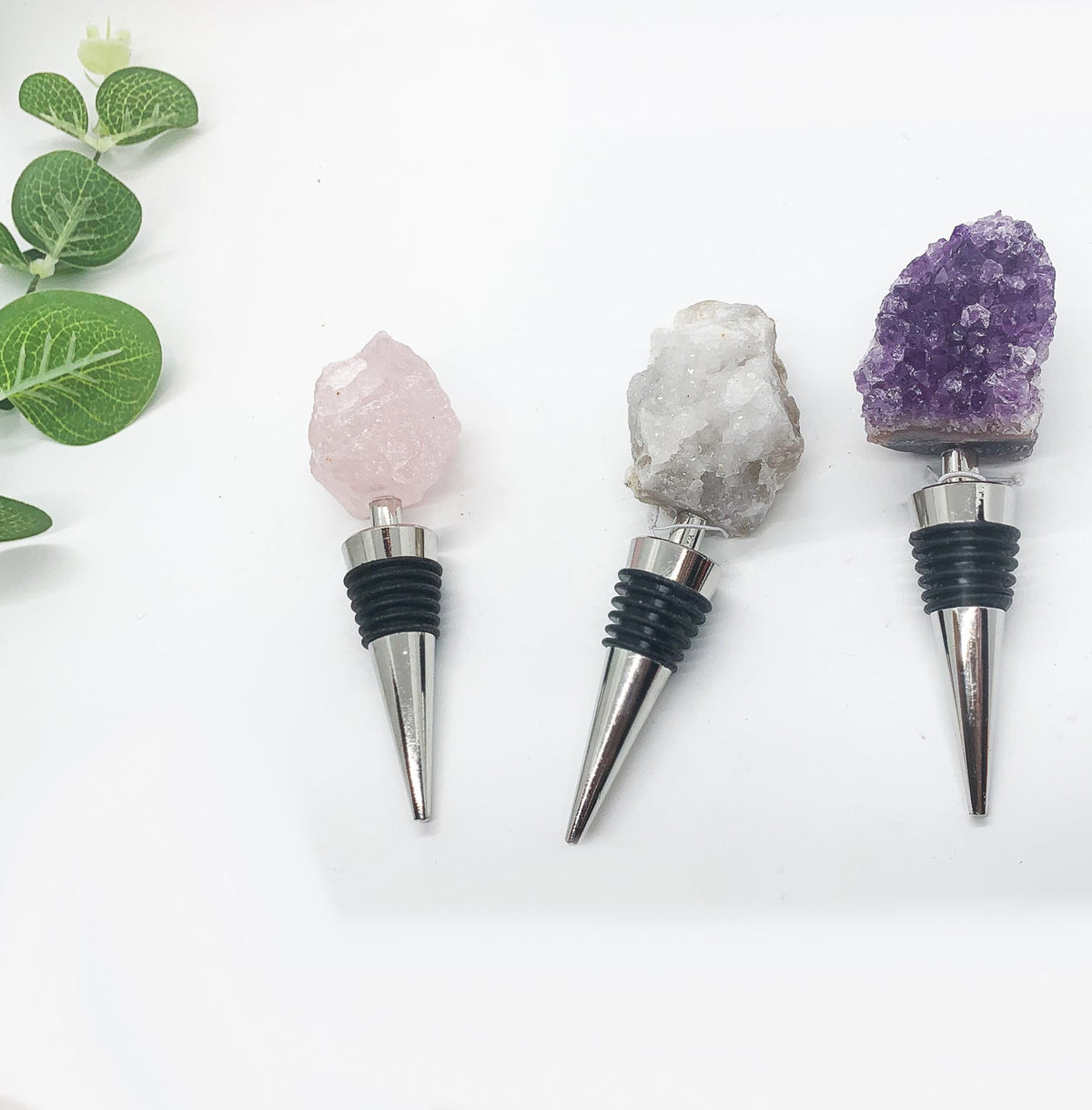 Crystal wine bottle stopper set with pink, clear, and purple stone tops and chrome tips