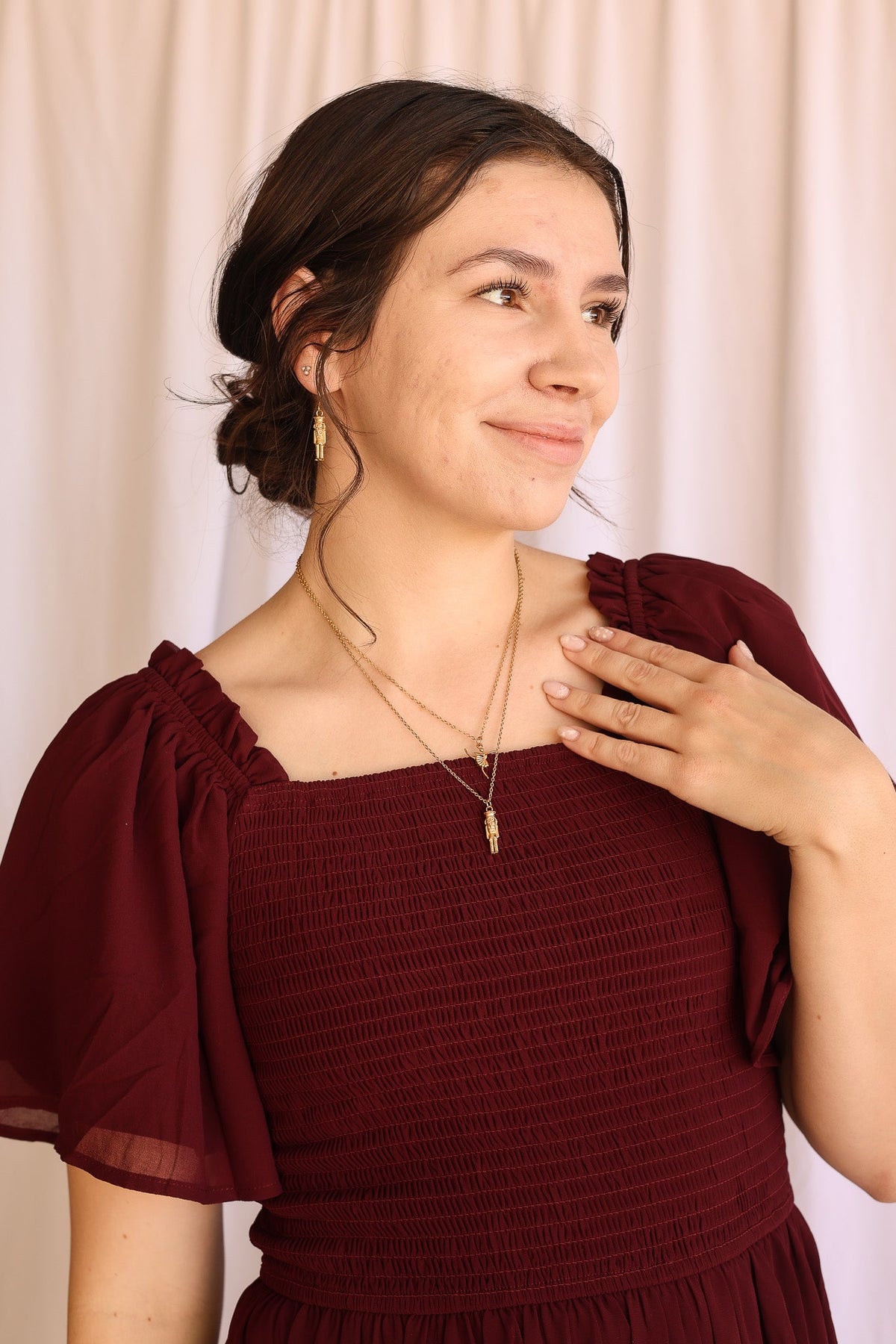 Gold nutcracker huggie hoop earring worn with layered necklaces