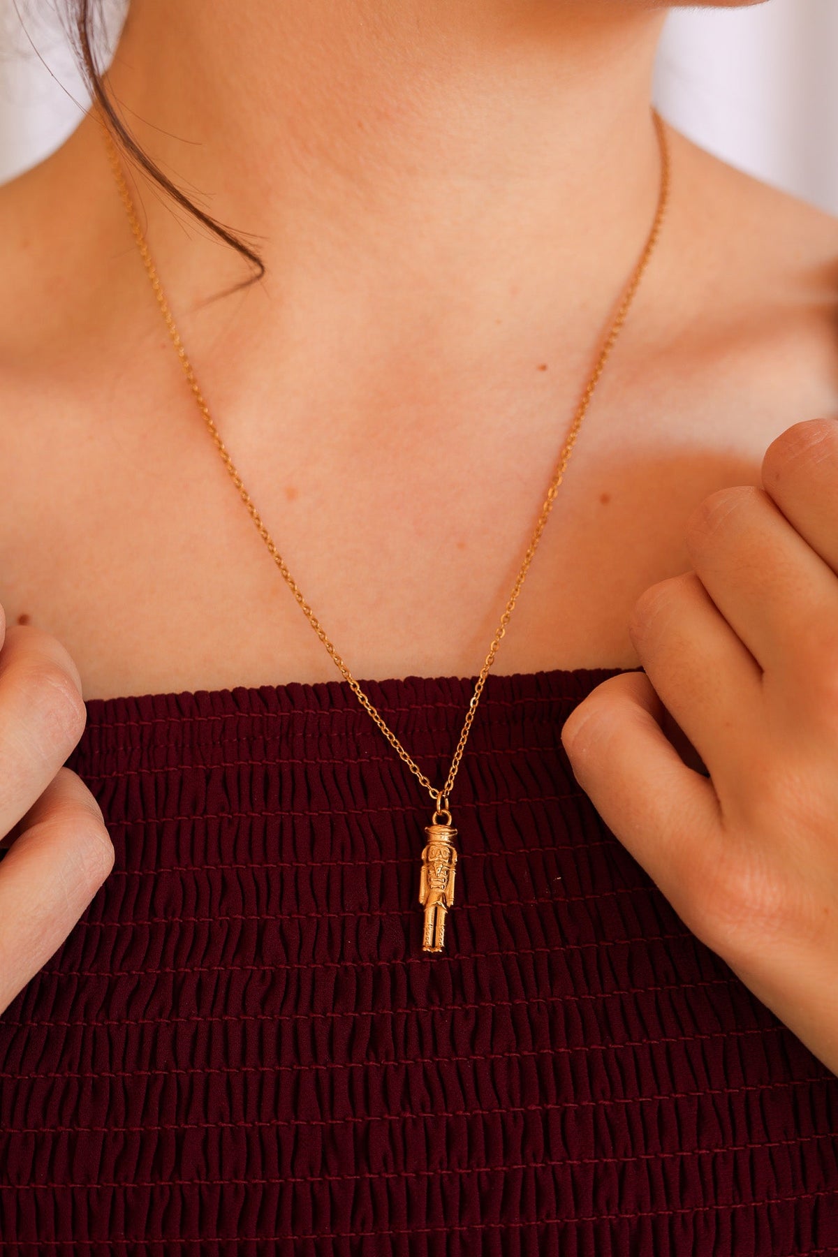 Gold nutcracker necklace worn with its small soldier pendant centered on the chest