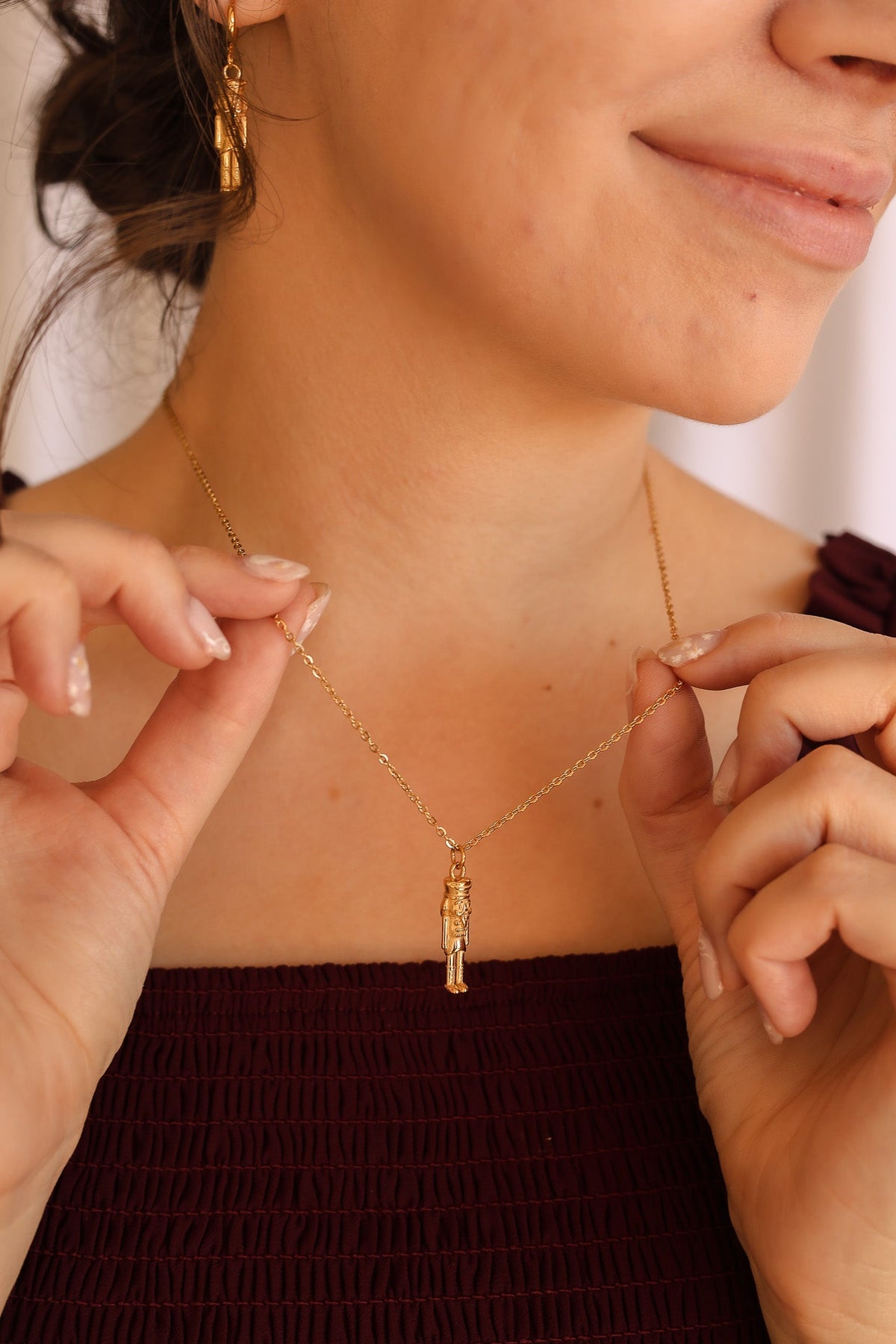 Nutcracker necklace with a small gold pendant on a fine chain, shown close up