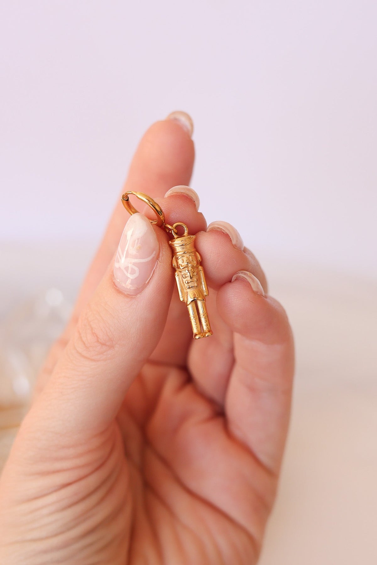 Close-up of a gold nutcracker huggie hoop and soldier charm
