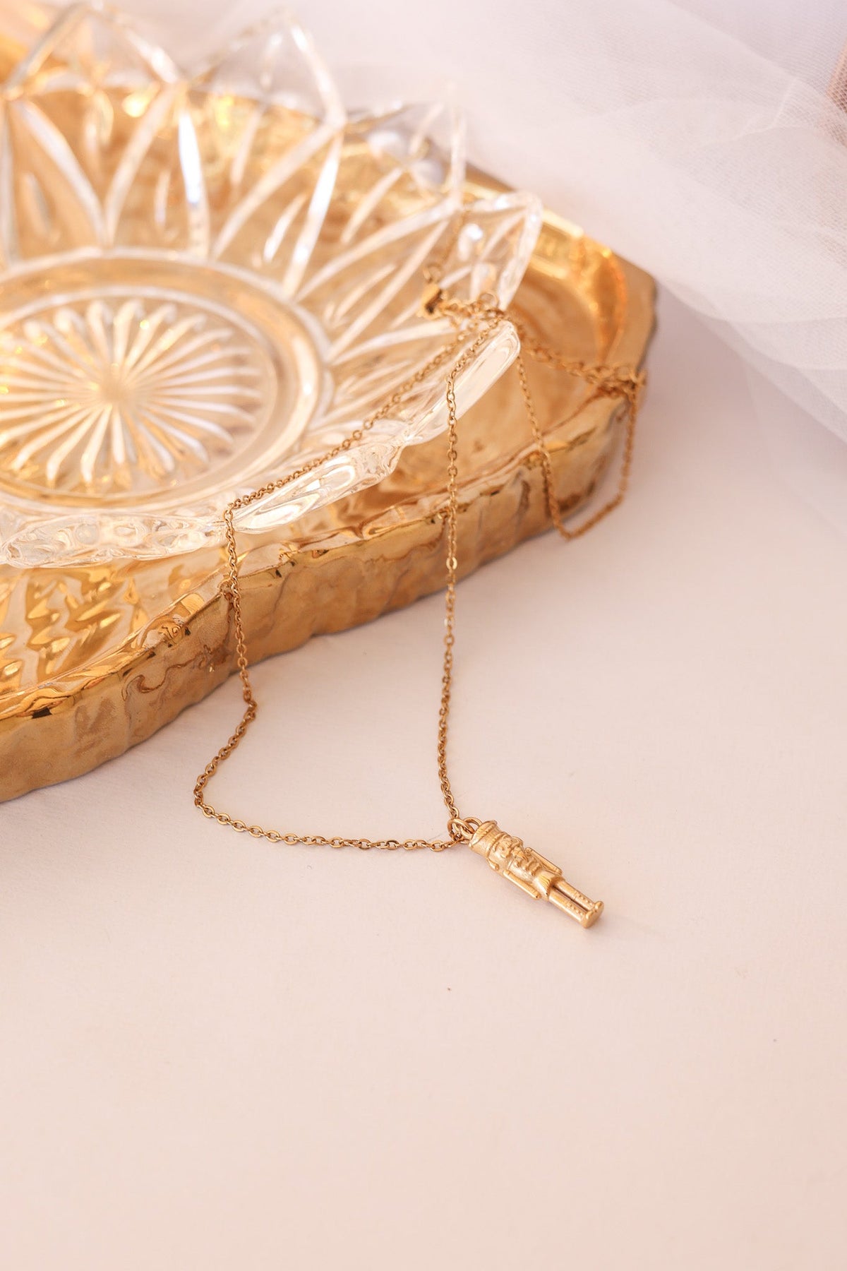 Gold nutcracker necklace laid out with its soldier pendant at the end of the chain