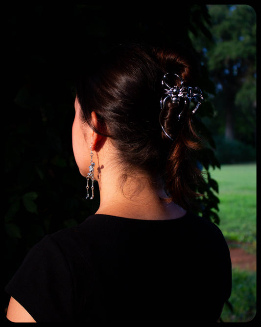 Silver-tone spider hair claw clipped on dark hair with curved wings
