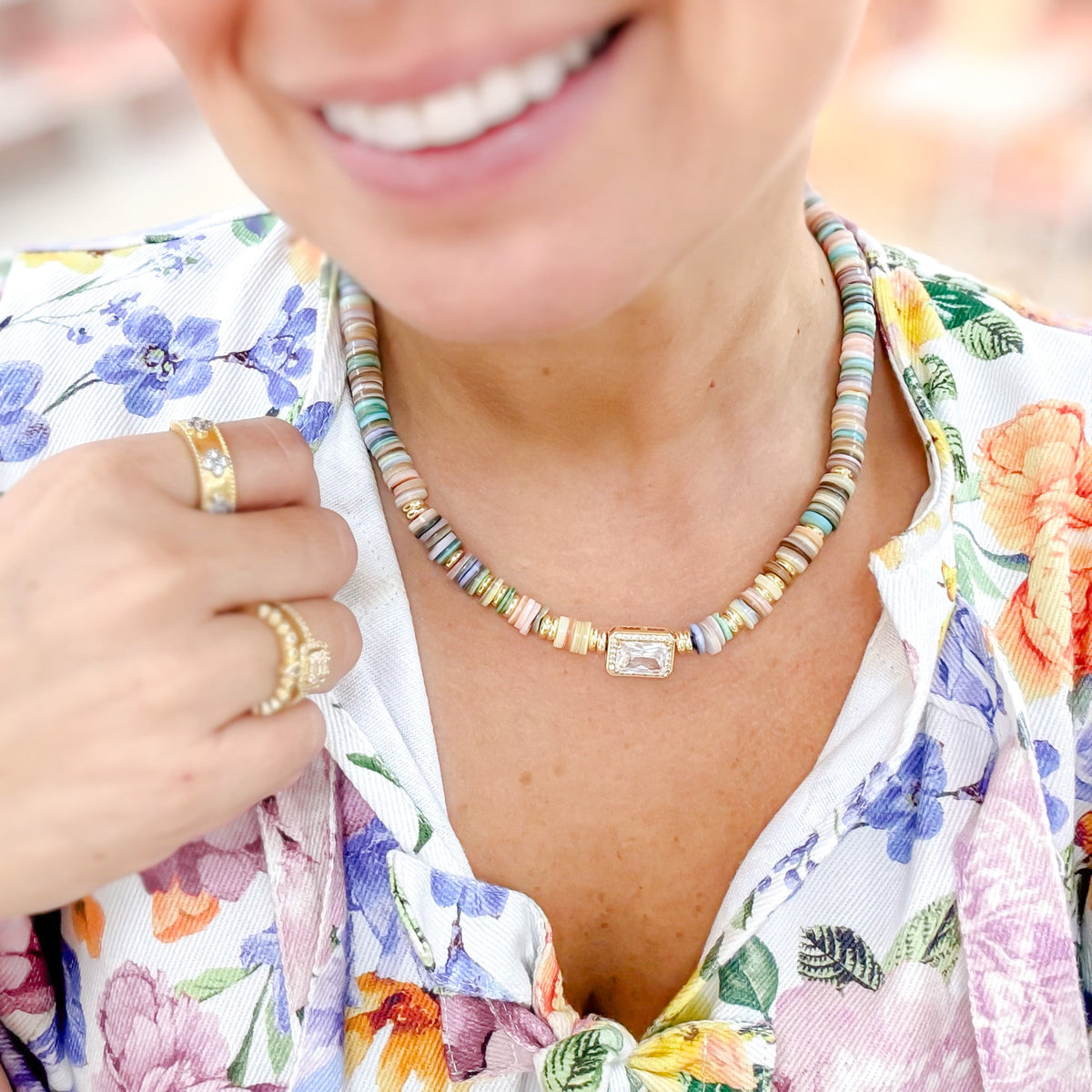 Gemstone beaded necklace on neckline with gold ring clasp; multicolor bead strands.