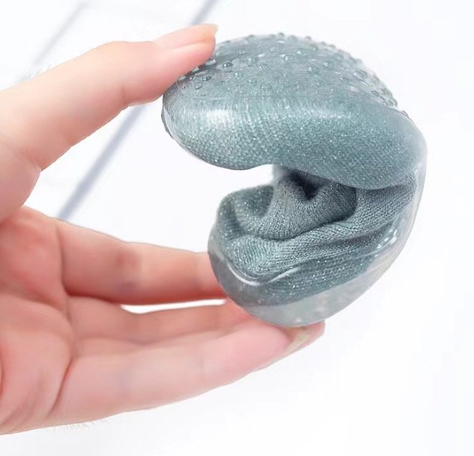 Teal baby sock shoe held up, clear sole and knit fabric upper shown