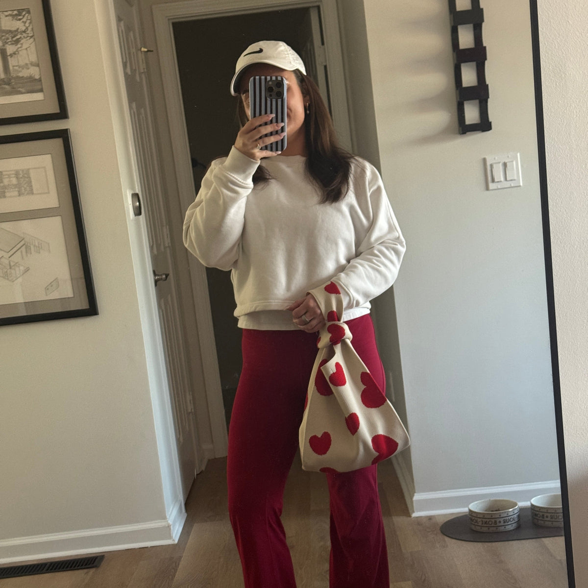 White handbag with red heart print and red tie handles