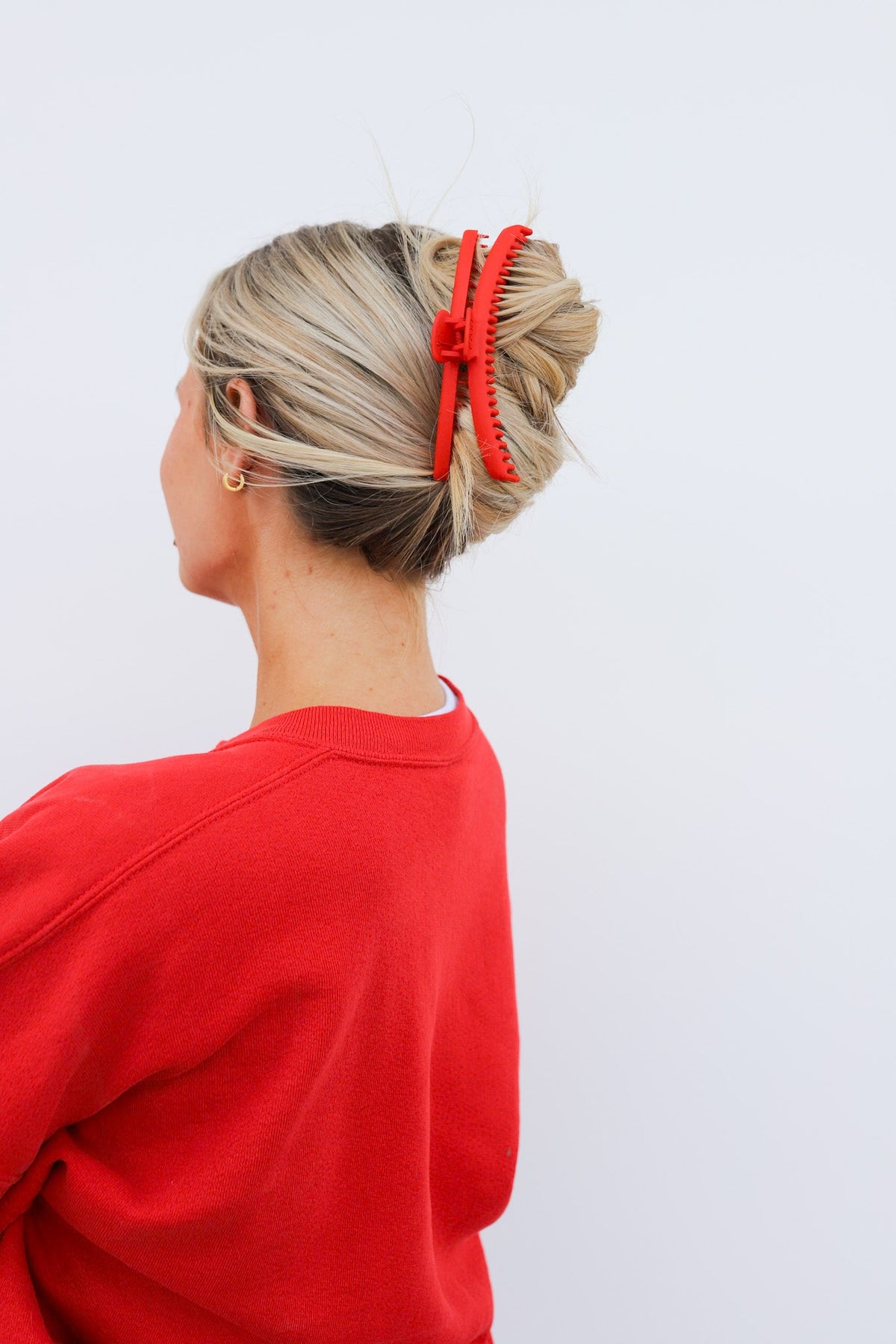 Red matte claw hair clip securing a blonde bun