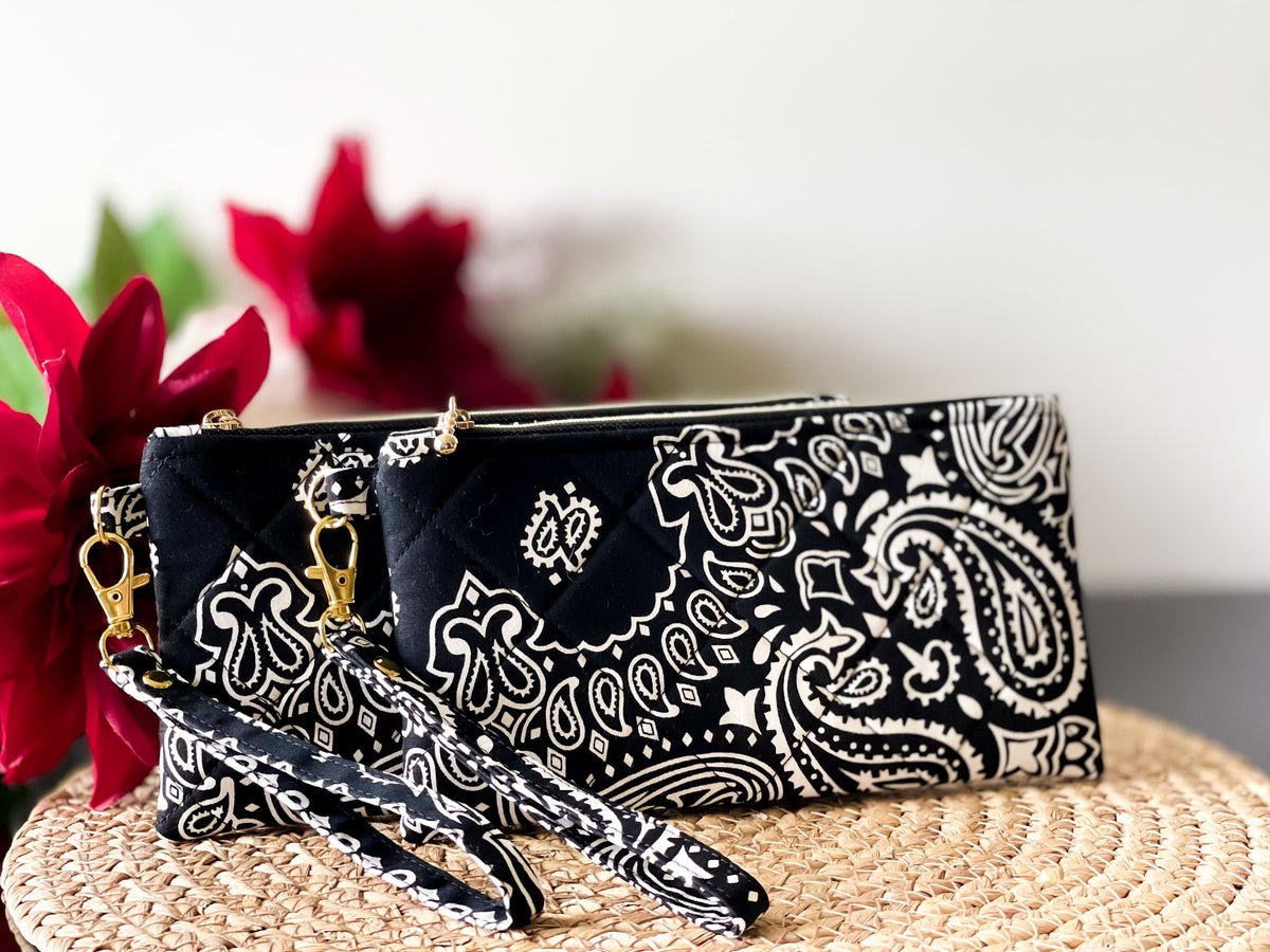 Quilted wristlet pouch with paisley print, gold chain wrist strap, and zip closure