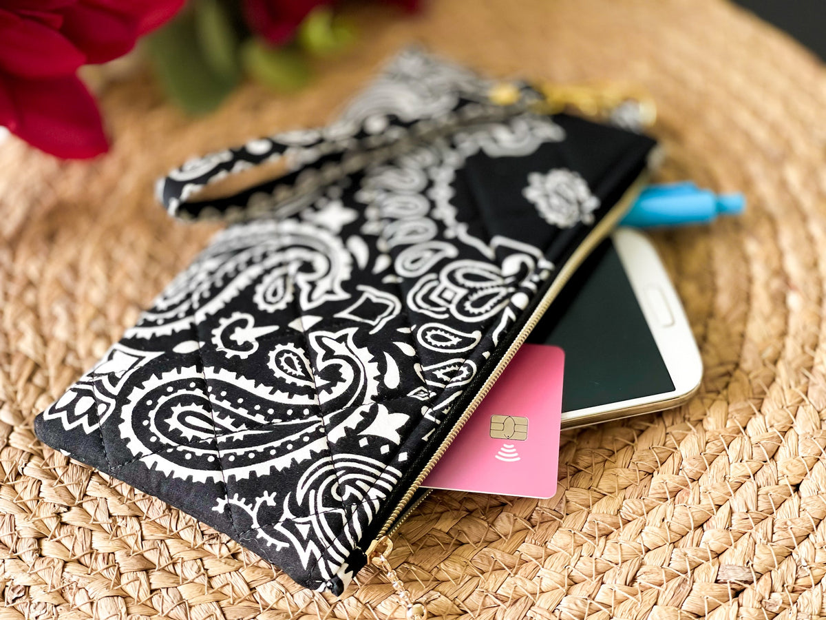 Quilted wristlet pouch opened with small card and phone inside; paisley navy exterior
