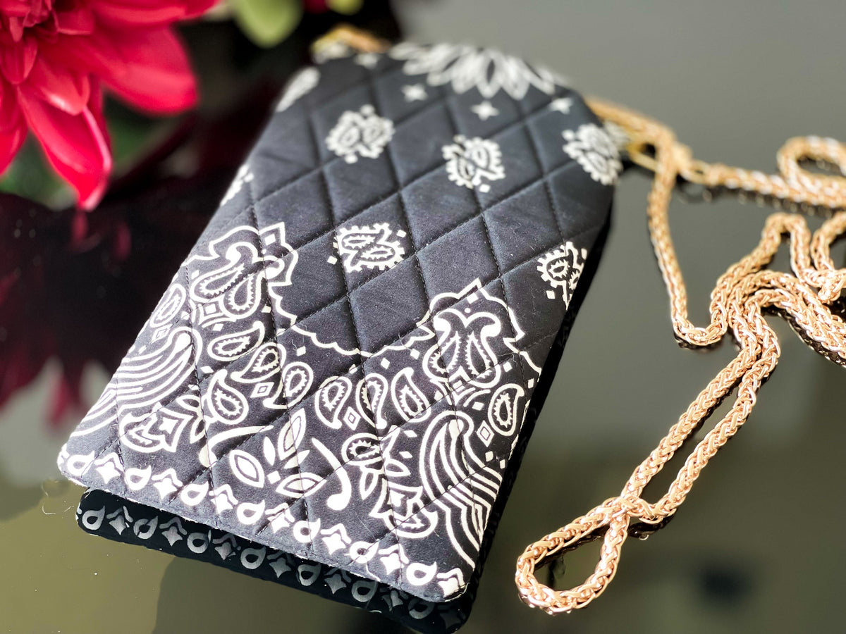 Black quilted phone sling with white paisley bandana print and gold chain strap