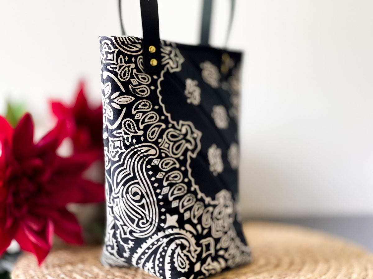 Navy bucket bag with white paisley print, side view with top handle openings.