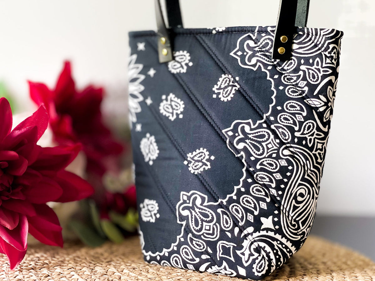 Navy bucket bag with white paisley bandana print, gold grommet top and handles.