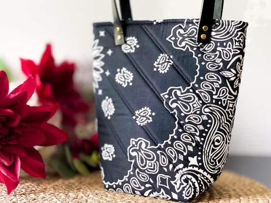 Navy bucket bag with white paisley bandana print, gold grommet top and handles.