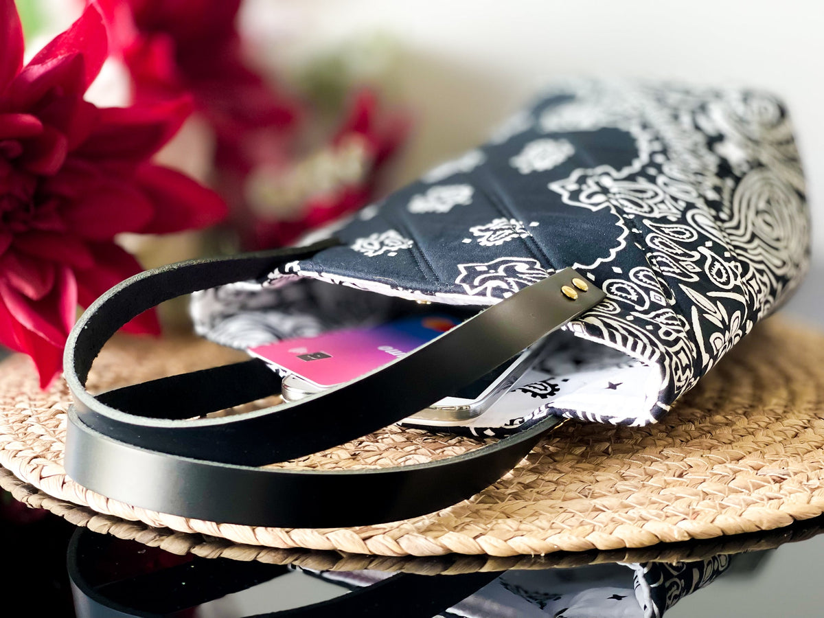 Navy bucket bag with white paisley print, black-and-silver straps on the base.