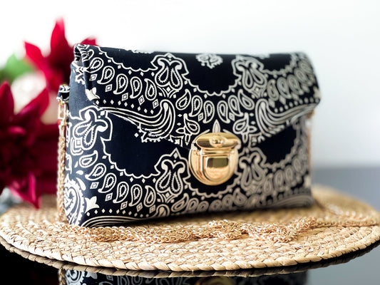 Black bandana print crossbody sling bag with gold-tone clasp and chain shoulder strap