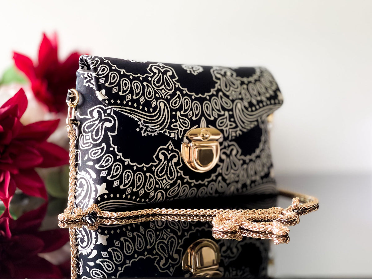 Black bandana print crossbody sling bag with gold-tone clasp and long chain strap