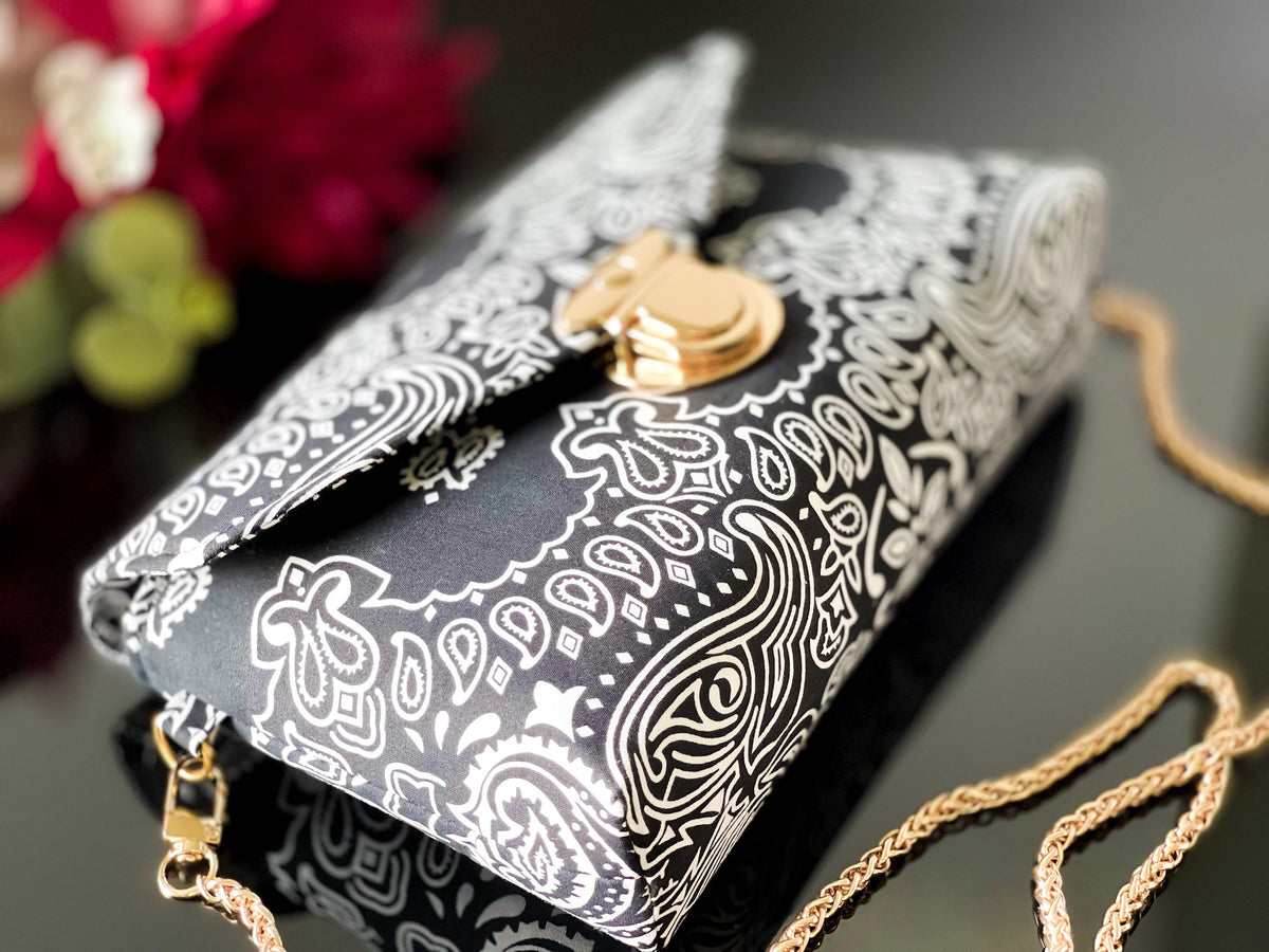 Black bandana print crossbody sling bag with gold-tone buckle clasp and chain strap