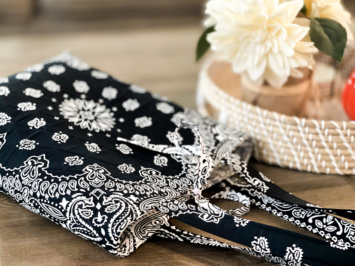Flat-lay view of medium tote bag in black with white bandana print and rope handles