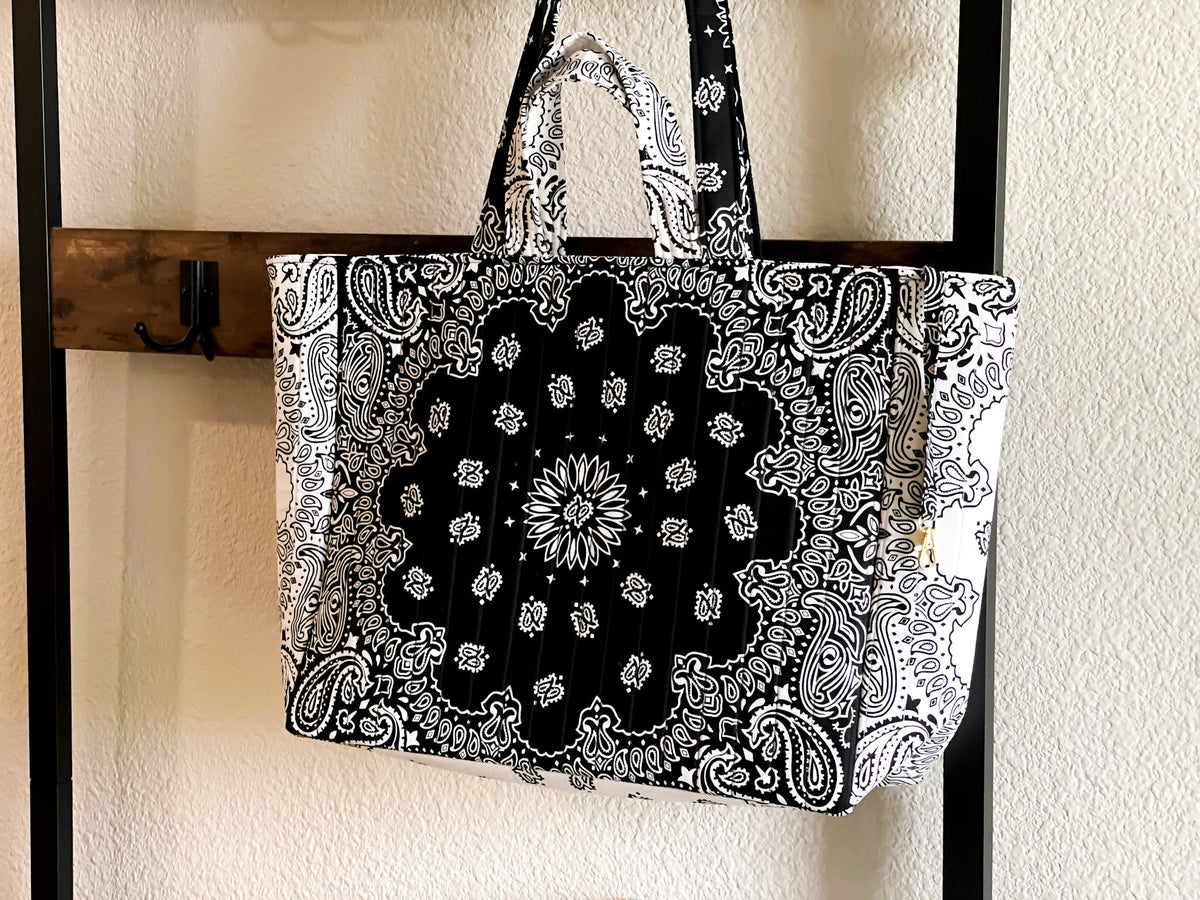 Large quilted tote bag hanging on hooks, black-and-white paisley print