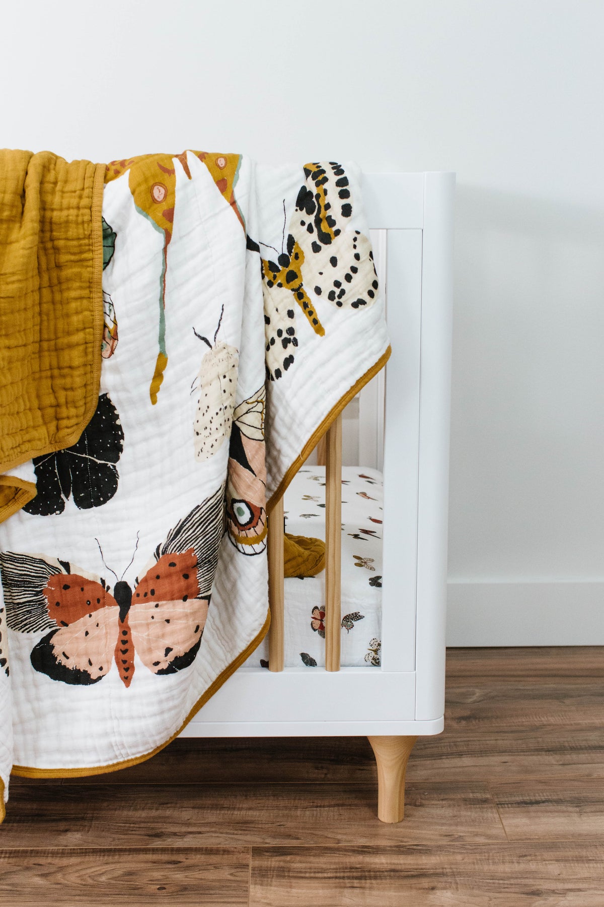 Butterfly print baby quilt draped over crib, showing black and orange butterflies