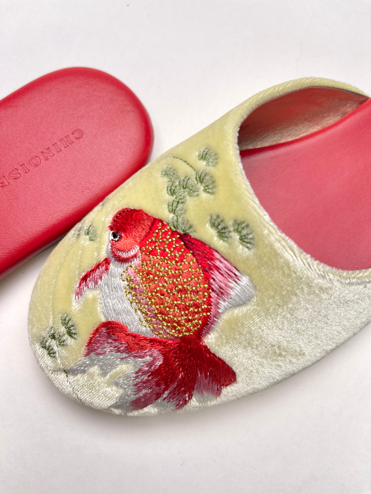 Close-up of lemon velvet mule with goldfish embroidery and green leaf details