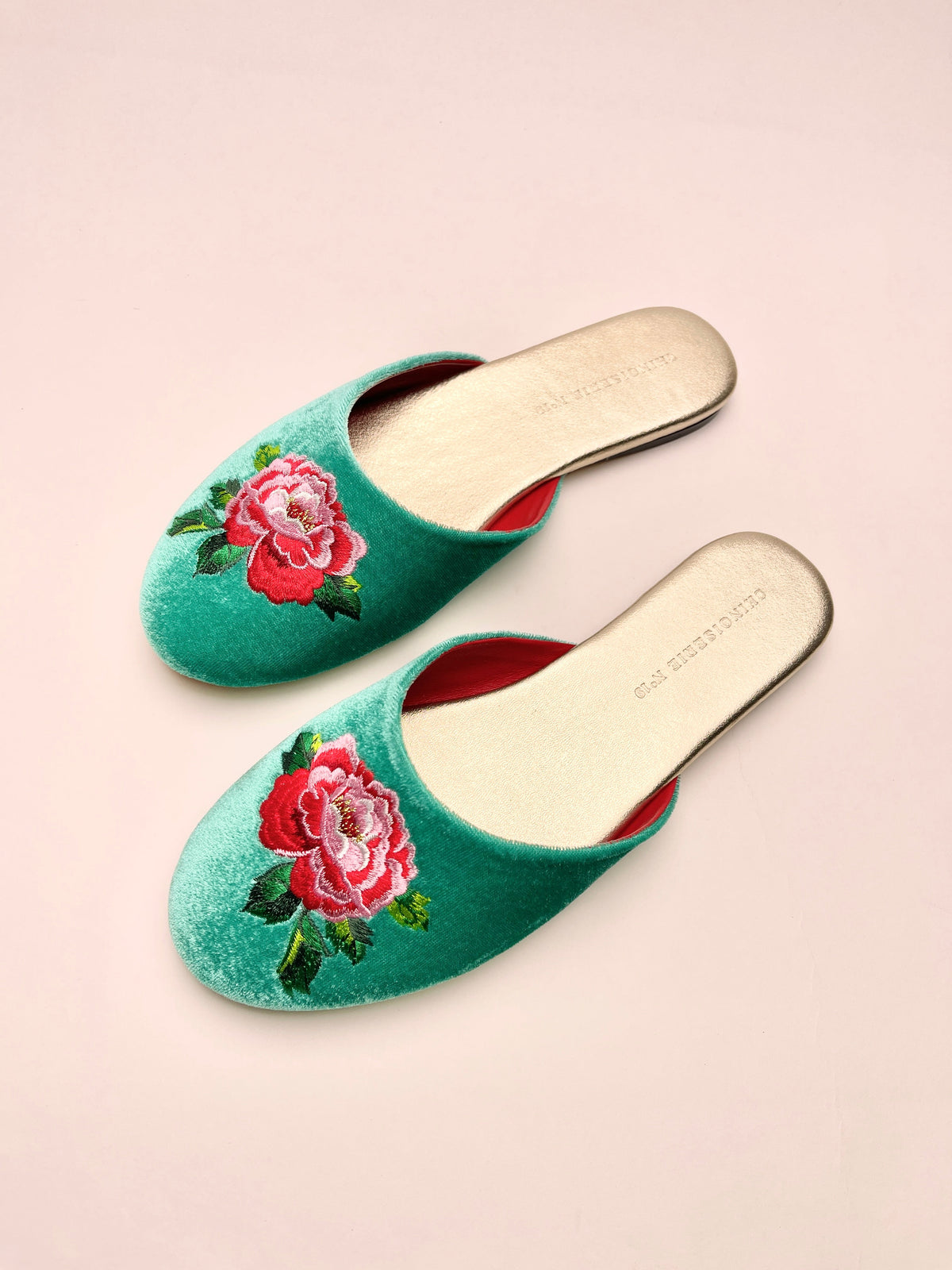 Jade green velvet mules with peony embroidery, angled top view of two