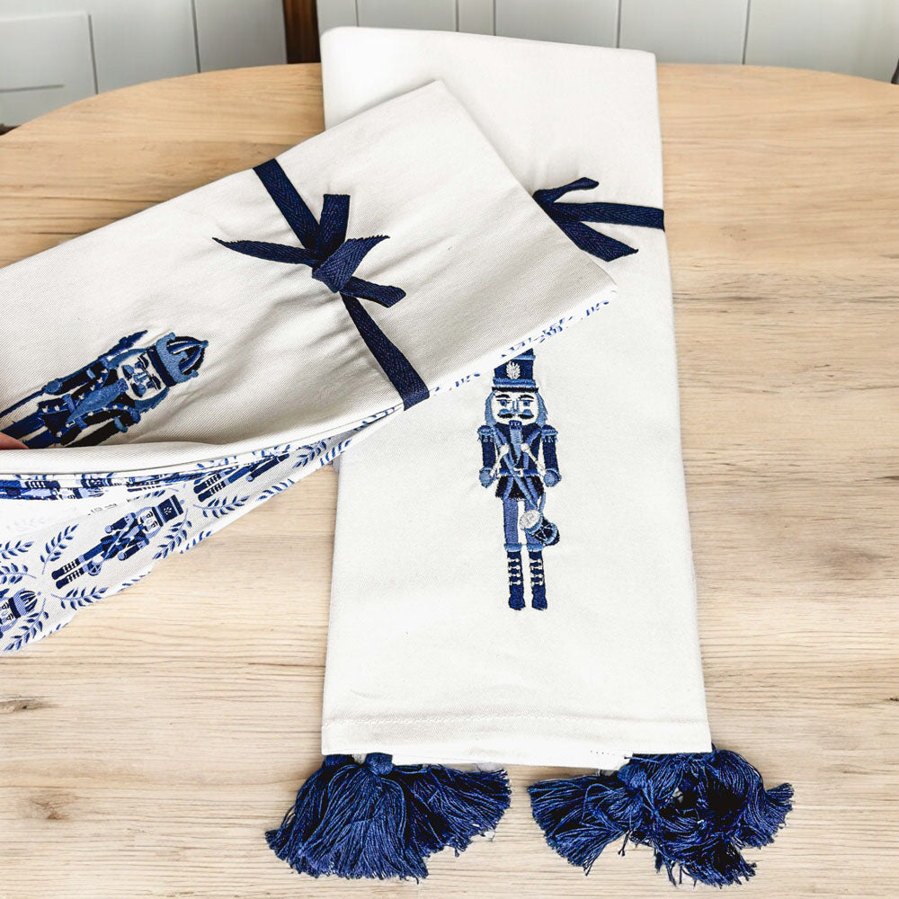 Two nutcracker tea towels in off-white with blue nutcracker prints and tassel fringe
