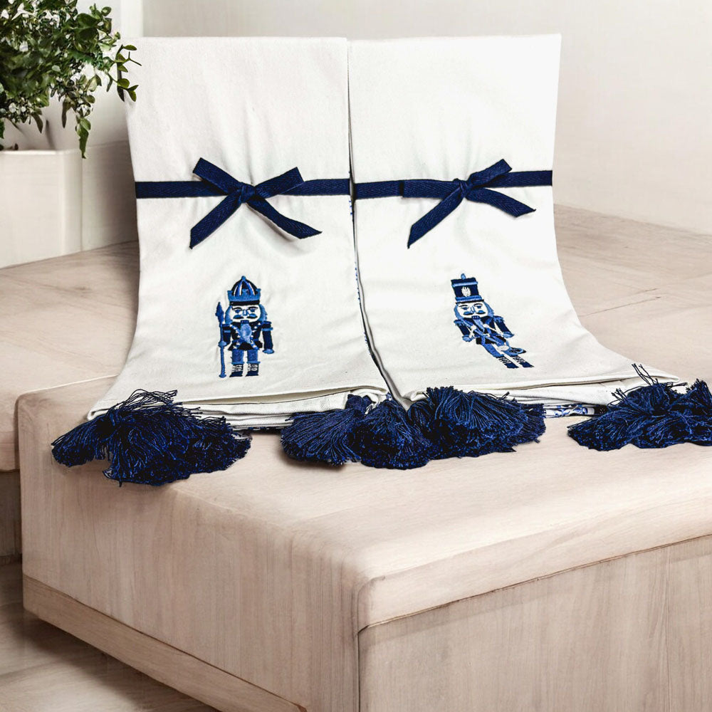 Pair of off-white nutcracker tea towels with blue bow details and tassel trim