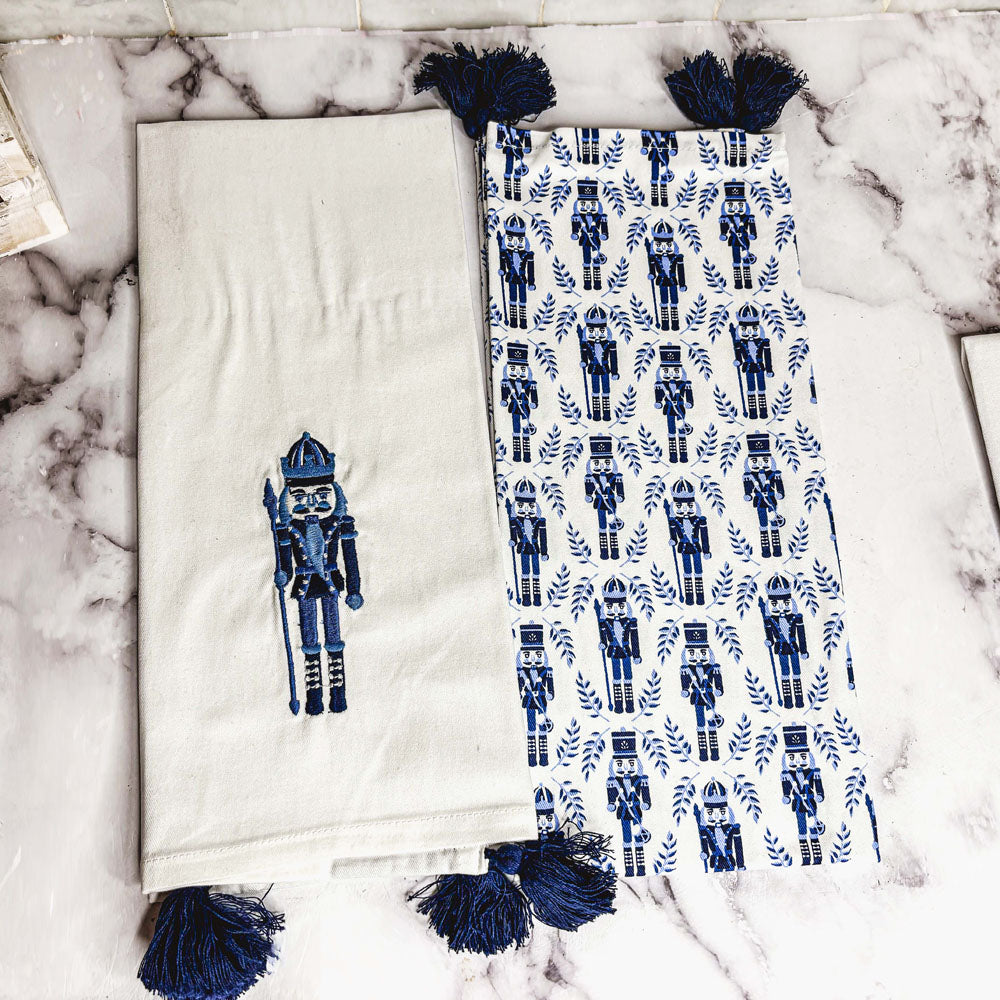 Off-white nutcracker tea towel with blue nutcracker applique and dark blue tassels