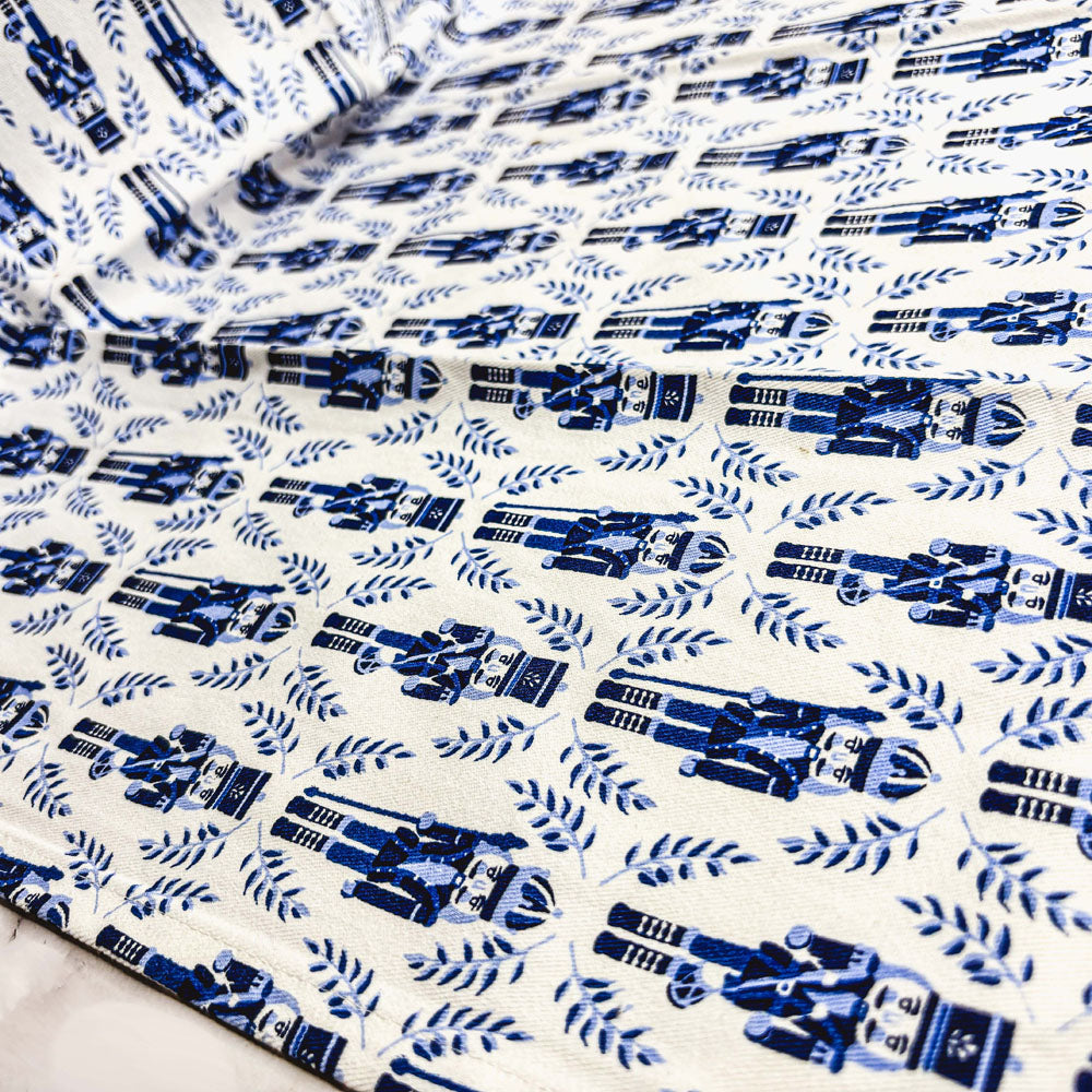 Close-up blue nutcracker print tea towel fabric with navy figures on white