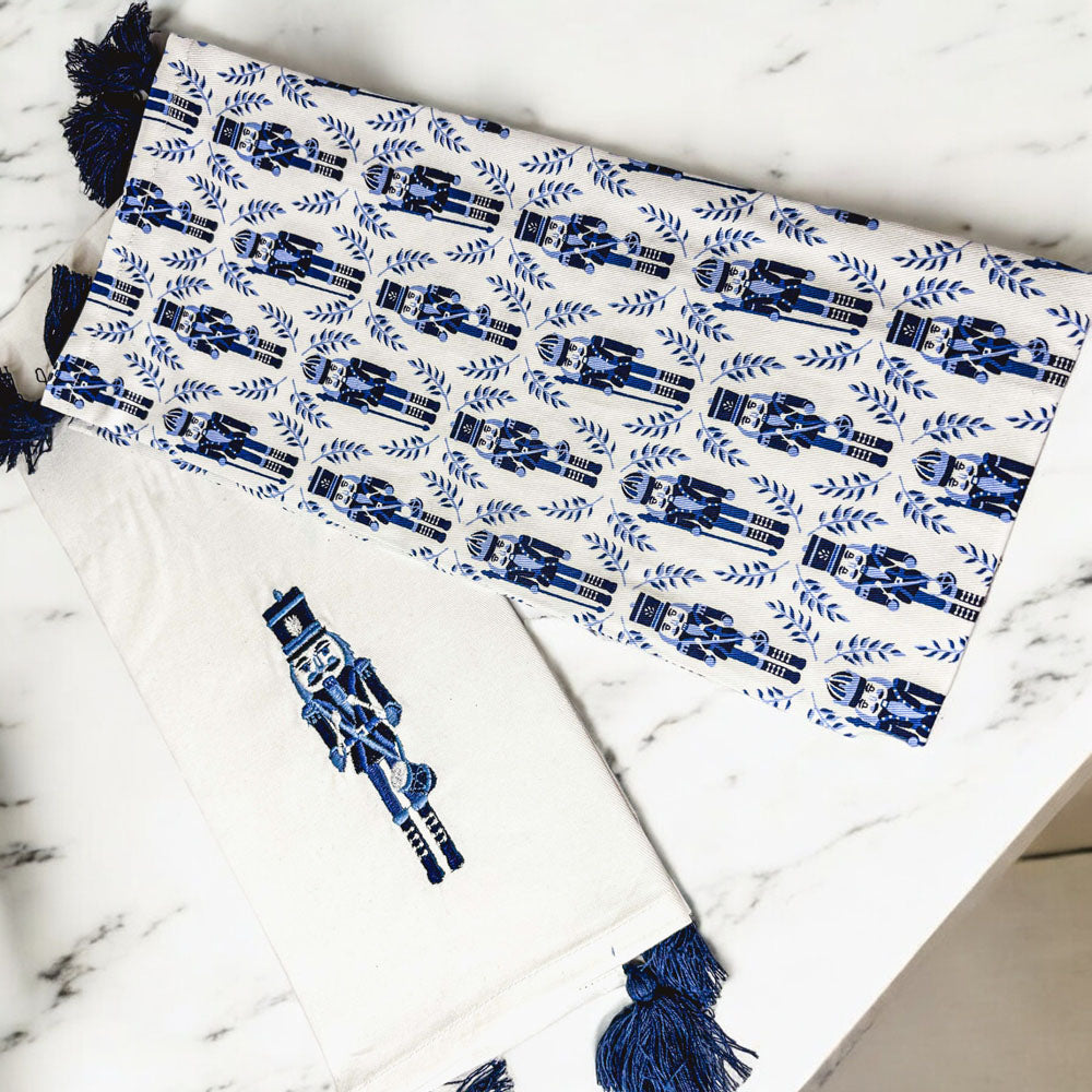 White and blue striped nutcracker tea towel with navy tassel fringe, laid flat