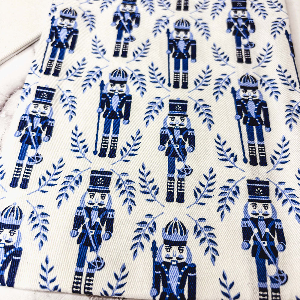 Close-up white tea towel fabric with repeating blue nutcracker pattern