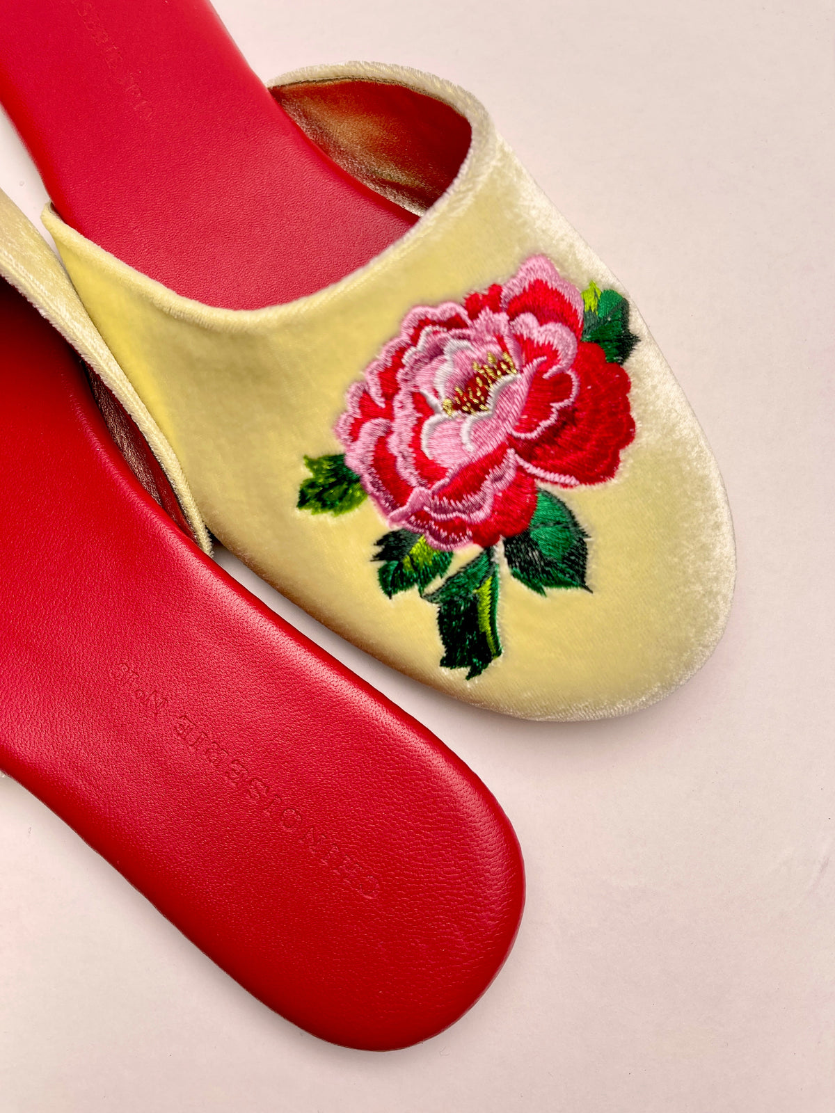 Close-up of lemon velvet mule with red peony embroidery and red outsole