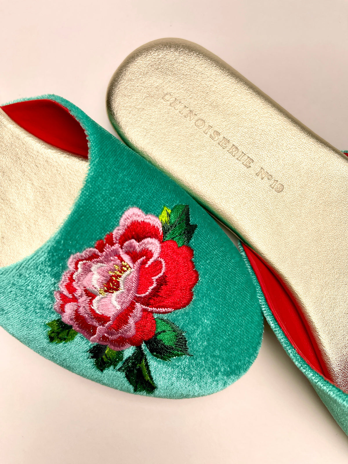 Close-up of jade green velvet mule with peony embroidery and red lining