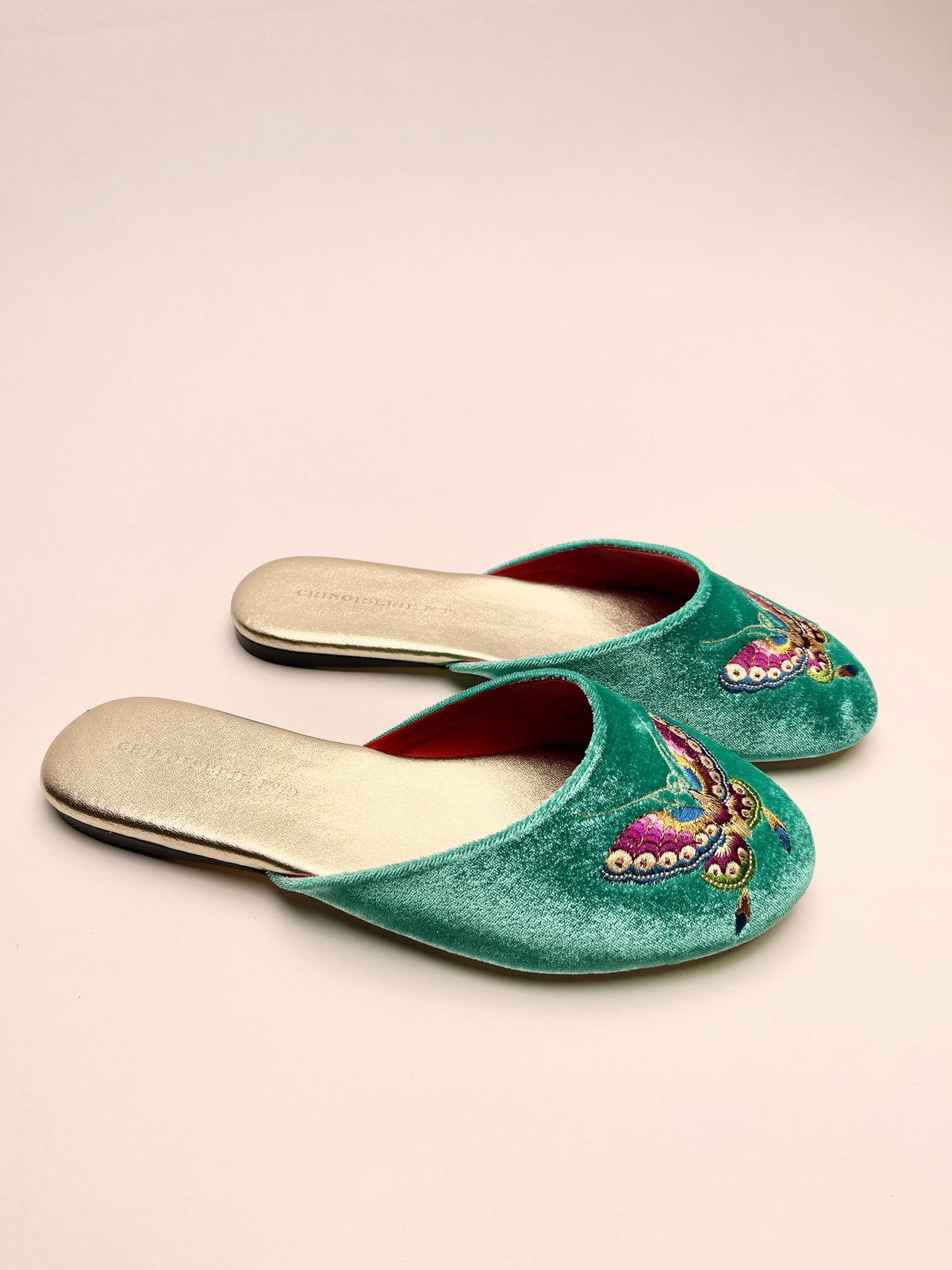 Pair of jade green velvet mules with butterfly embroidery, red lining, flat sole.