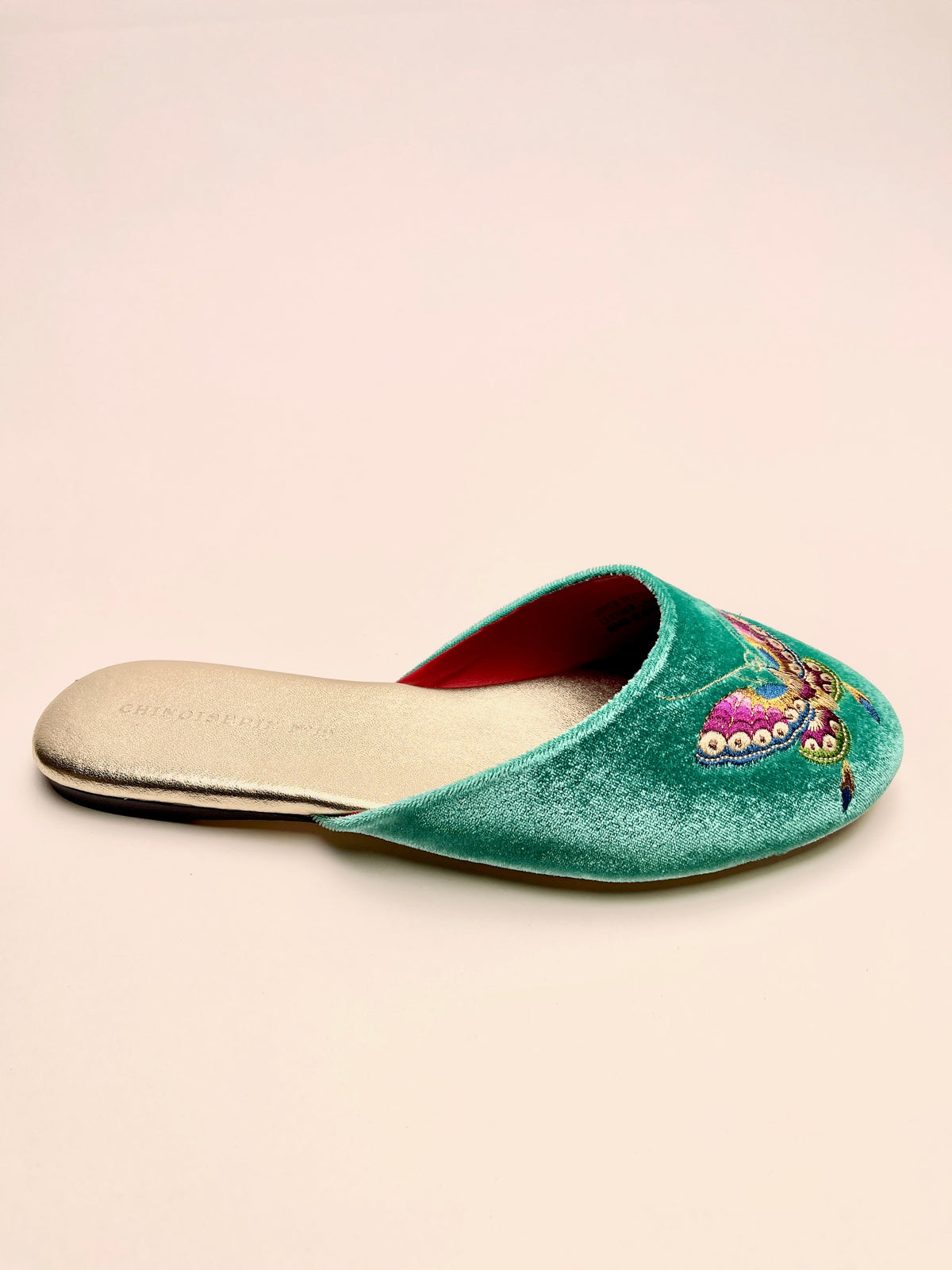 Jade green velvet mule slipper with butterfly embroidery and red lining, side view.