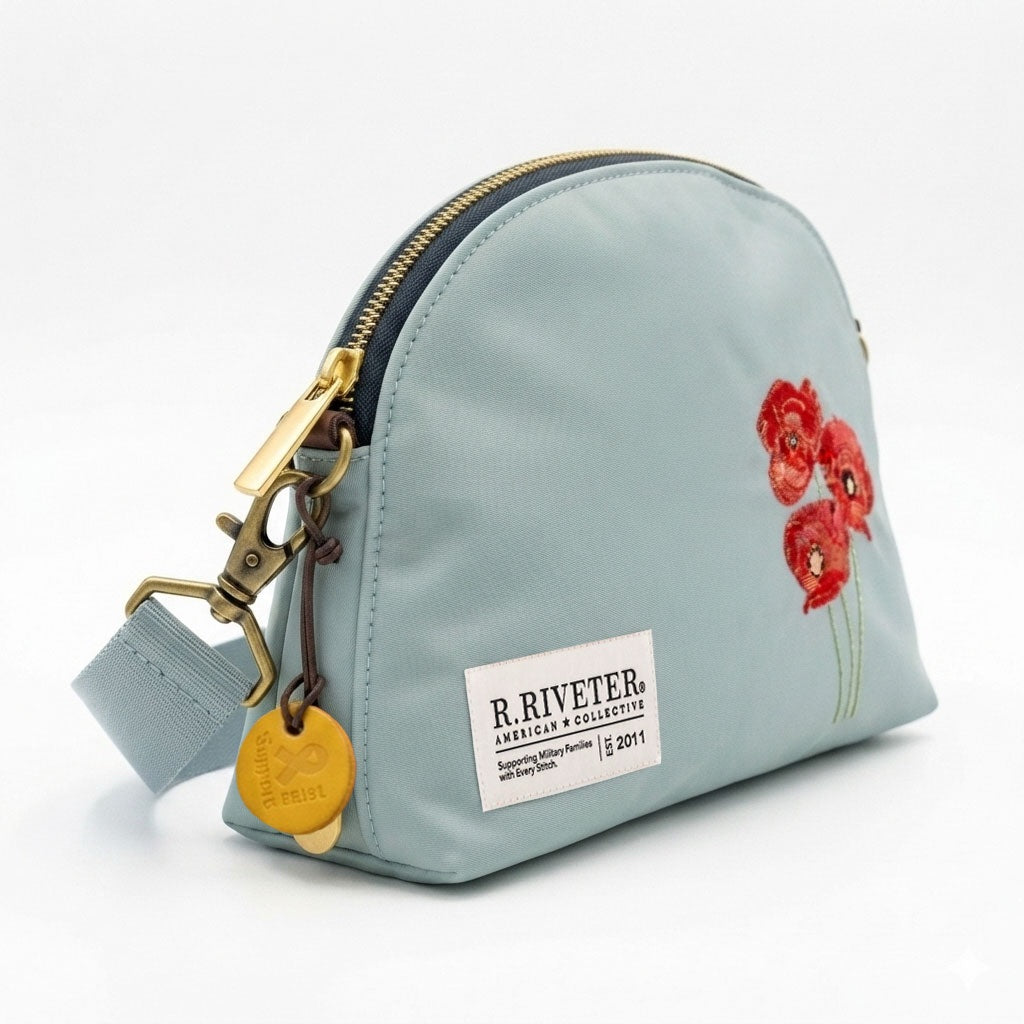 Light blue nylon bag with gold zipper, red embroidered poppies, hanging key charm and logo patch