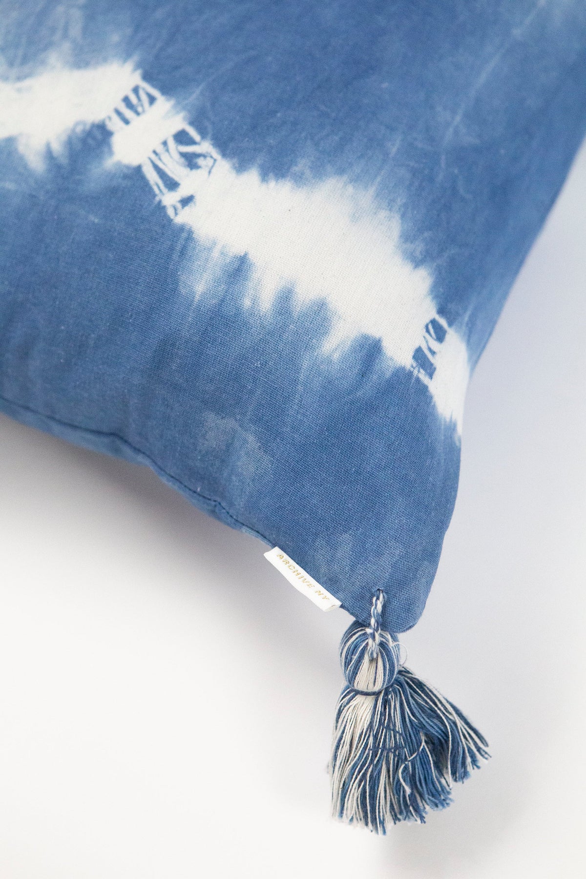Indigo shibori lumbar pillow corner with tassel trim and white streak